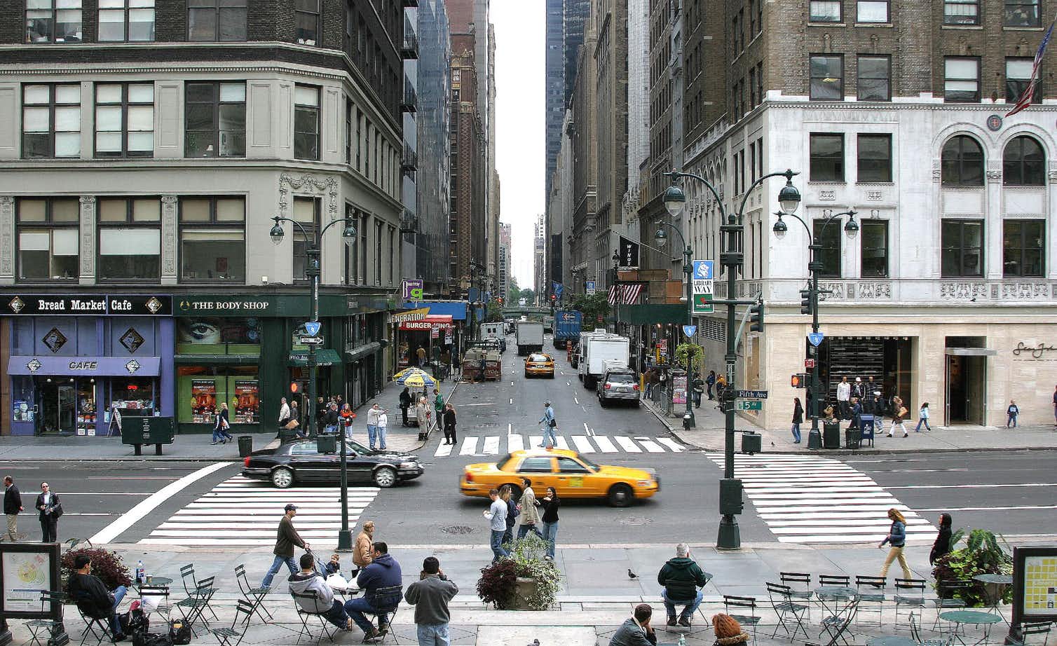 A busy city street scene with a yellow taxi cab