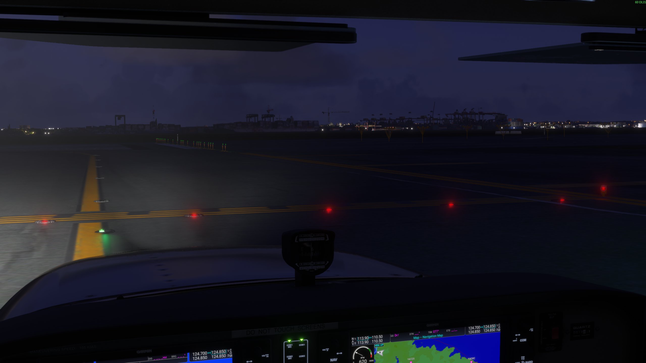 Cockpit view of red stop bar lights and green taxiway lights at an airport at night