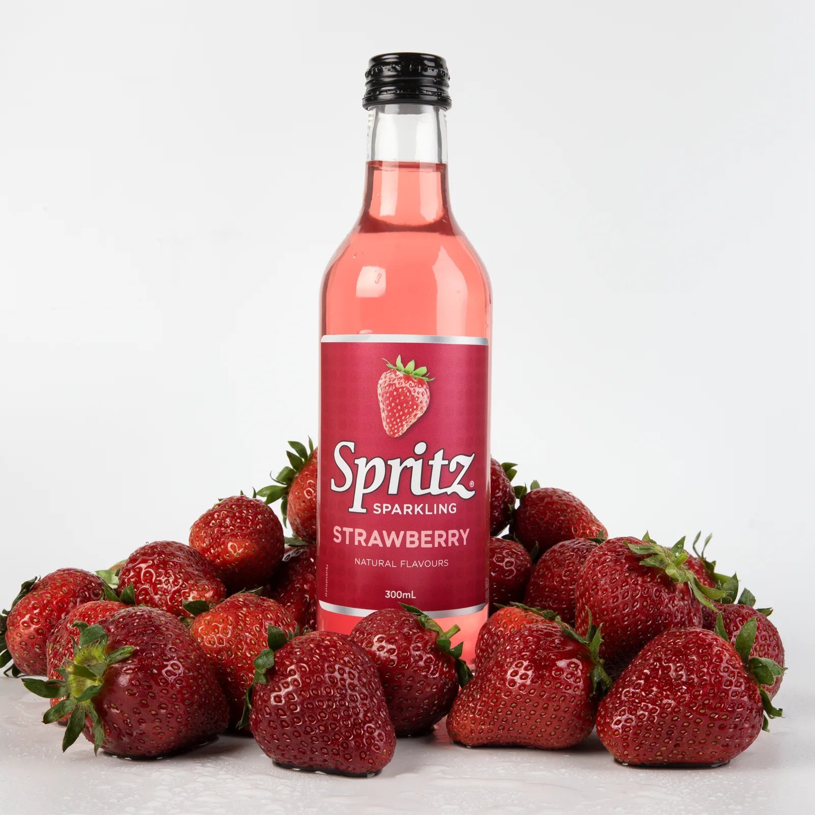 Output: the Spritz bottle standing in a pile of wet strawberries on a white background