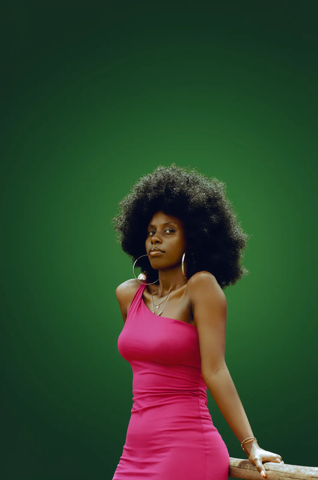 Output: the same woman in a fuchsia dress against a green studio gradient