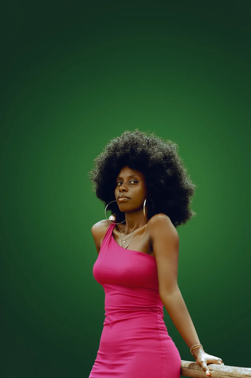 Output: the same woman in a fuchsia dress against a green studio gradient
