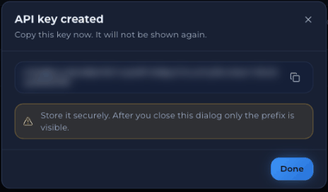 API key created dialog with a blurred key, a copy icon and the warning Store it securely. After you close this dialog only the prefix is visible