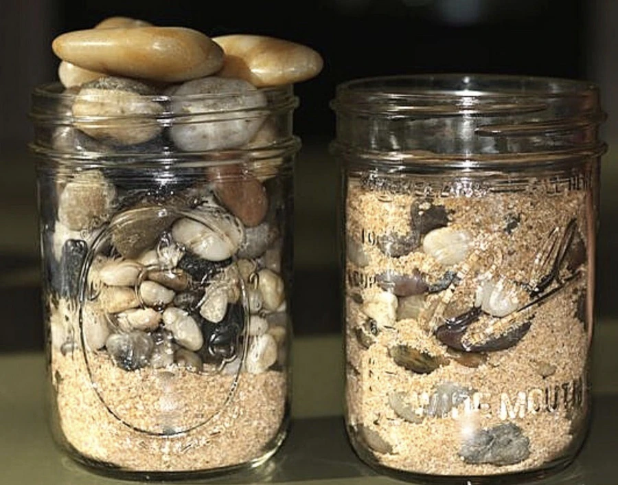 Two jars showing stones placed before sand and sand placed before stones