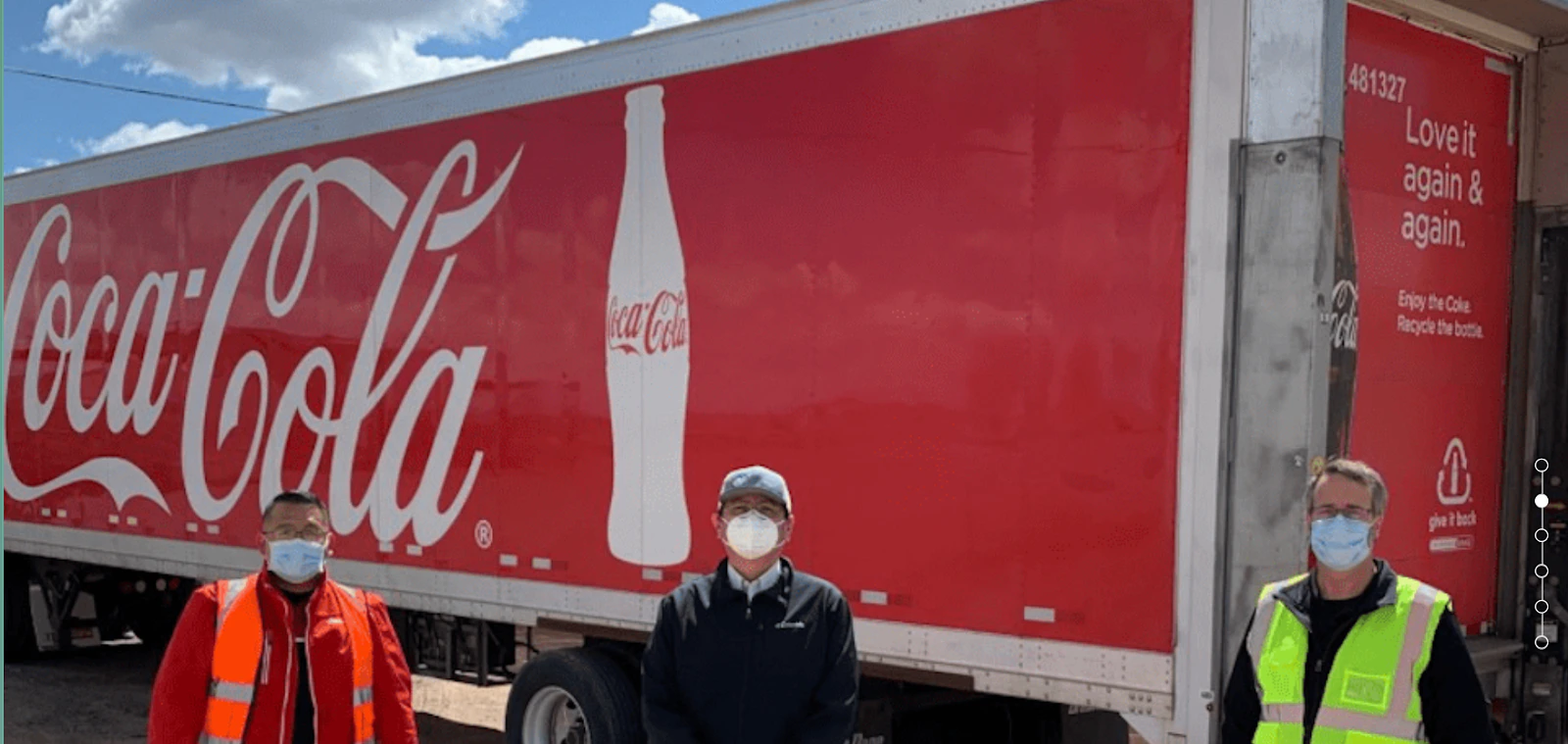 3 people standing in front of a Coca-Cola truck