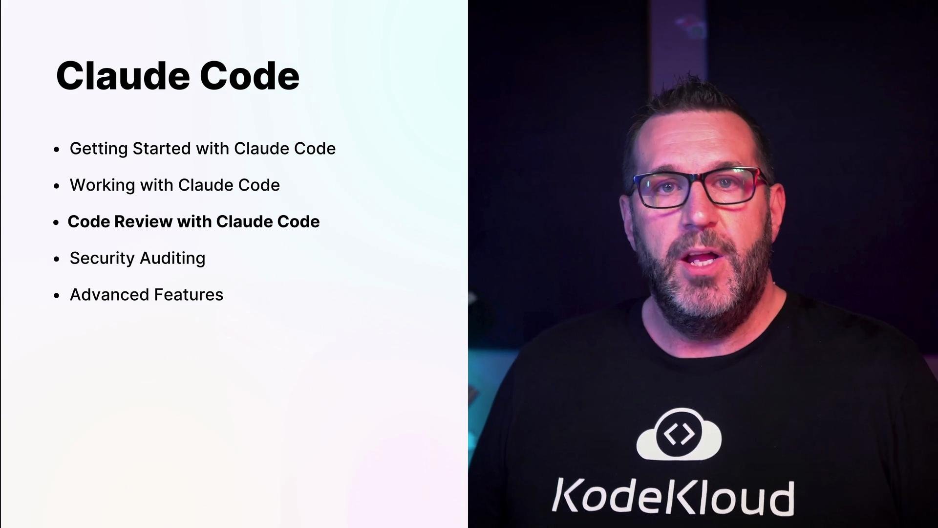 A split-screen slide titled "Claude Code" with bullet points (Getting Started, Working, Code Review, Security Auditing, Advanced Features) on the left. On the right, a bearded man wearing glasses and a KodeKloud T‑shirt speaks toward the camera.