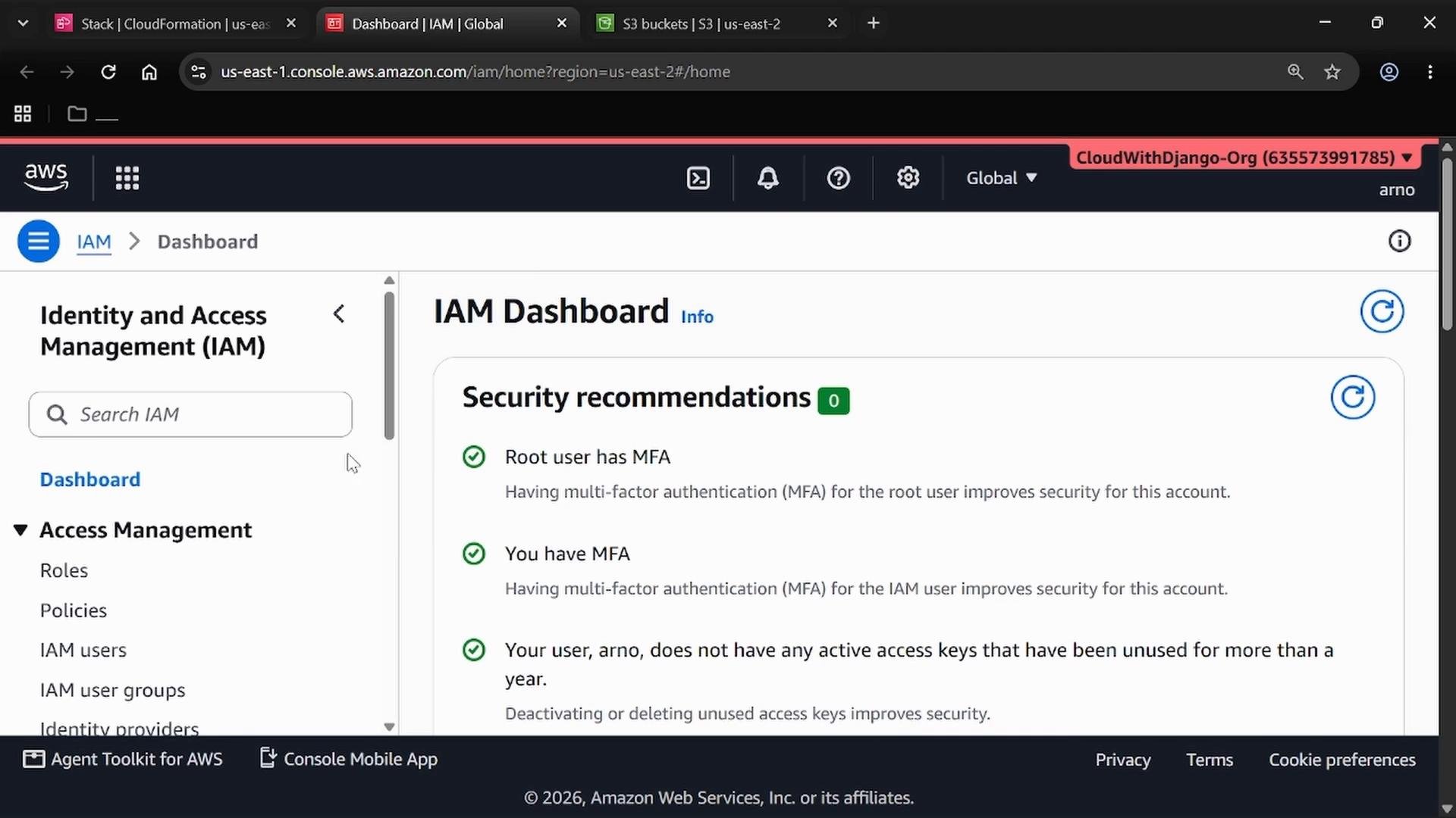 A screenshot of the AWS Identity and Access Management (IAM) Dashboard showing security recommendations such as MFA status and unused access key info. The left sidebar displays IAM navigation items (Roles, Policies, IAM users) while the main panel lists green checkmarks for compliant settings.