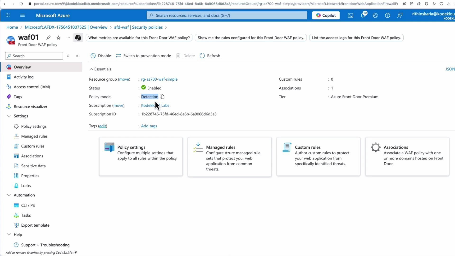 A screenshot of the Microsoft Azure portal showing the "waf01" Front Door WAF policy Overview page, with essentials like resource group, status (Enabled) and policy mode (Detection) displayed. The page also shows tiles for Policy settings, Managed rules, Custom rules, and Associations.