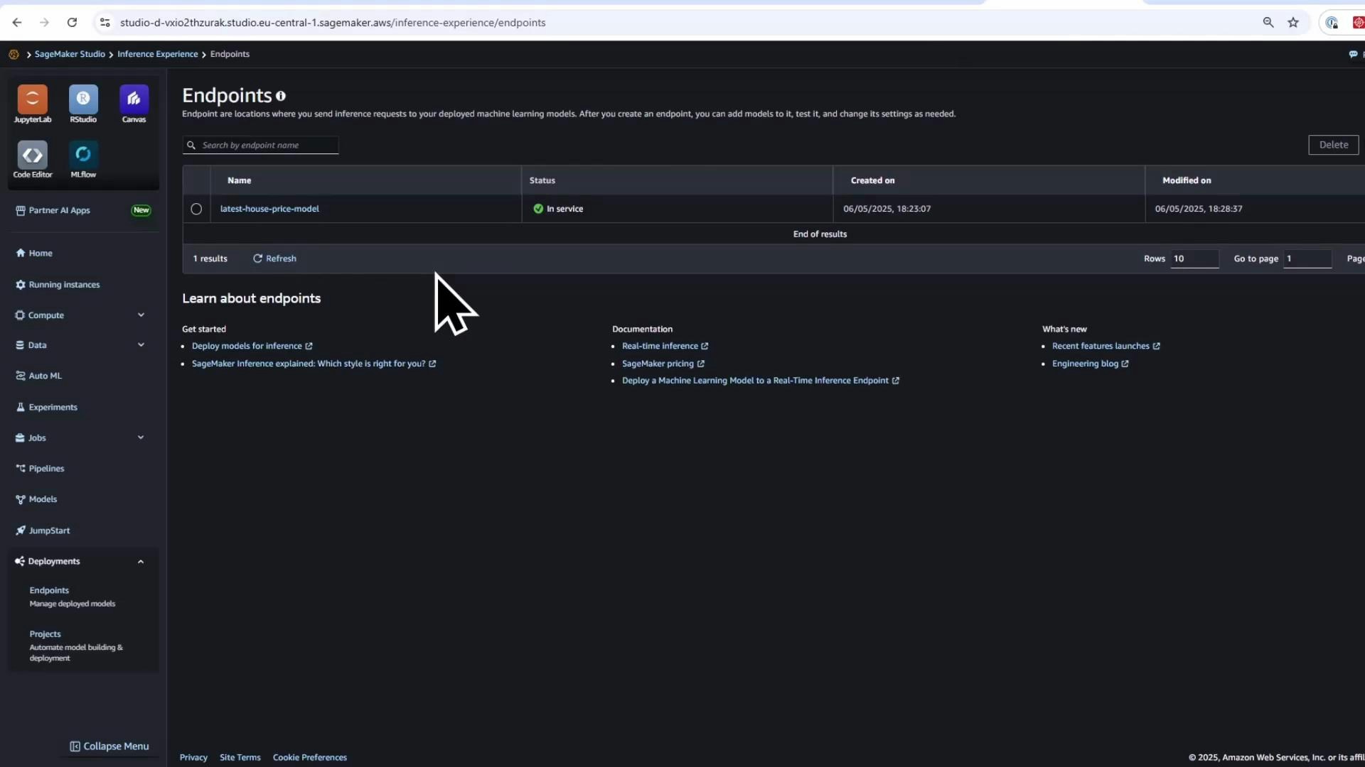 A screenshot of the Amazon SageMaker Studio "Endpoints" page showing one deployed endpoint named "latest-house-price-model" with status "In service." The dark-themed UI includes a left navigation sidebar and a large mouse cursor hovering over the endpoint list.