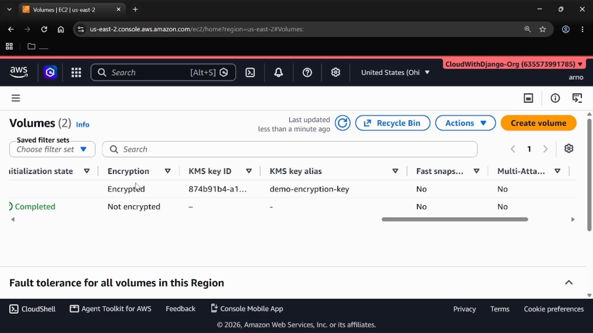 A screenshot of the AWS EC2 Volumes console listing two volumes with columns for encryption status, KMS key ID/alias, initialization state and other properties. The top bar shows region/account controls and action buttons like "Create volume" and "Recycle Bin."