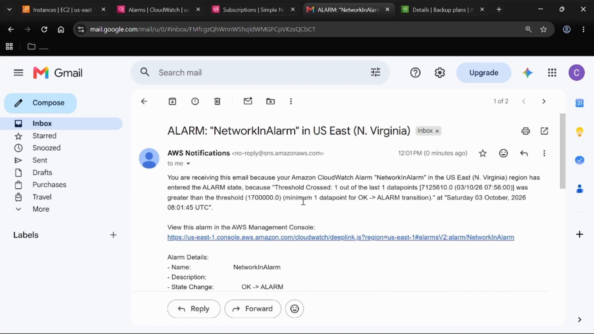 A screenshot of a Gmail inbox displaying an AWS Notifications email titled "ALARM: 'NetworkInAlarm' in US East (N. Virginia)" describing a CloudWatch alarm. The message content and links to the AWS console are visible with standard Gmail UI elements.