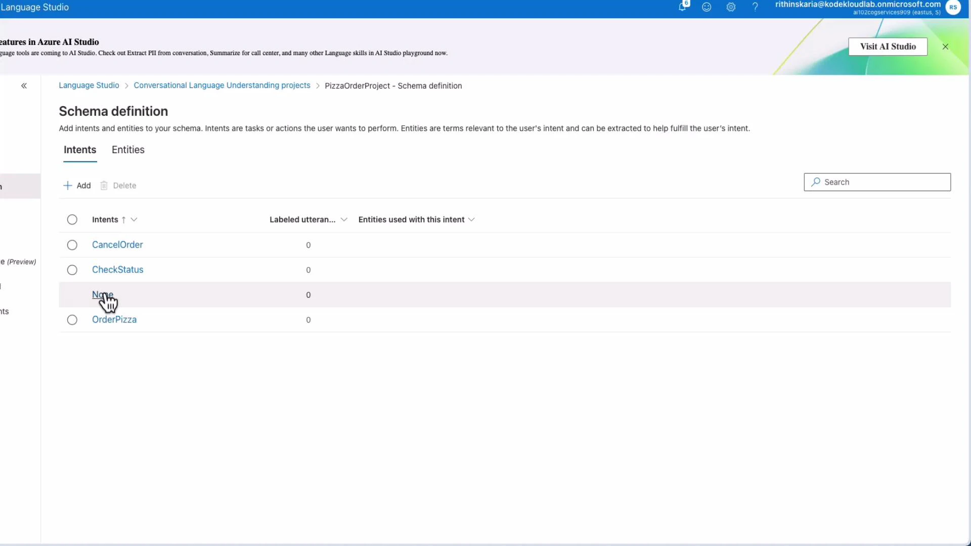 A screenshot of Azure Language Studio's "Schema definition" page for a PizzaOrderProject listing intents (CancelOrder, CheckStatus, None, OrderPizza) with a hand cursor over "None." The table shows columns for labeled utterances and entities used with each intent, all currently set to 0.