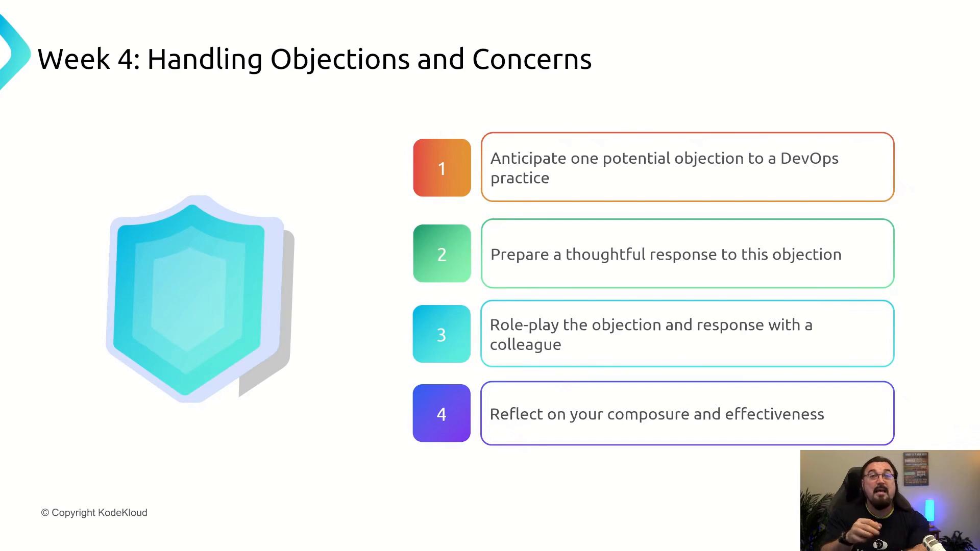 A presentation slide titled "Week 4: Handling Objections and Concerns" listing four steps for dealing with DevOps objections (anticipate an objection, prepare a response, role‑play, and reflect). The slide also shows a shield graphic on the left and a small webcam view of the instructor in the bottom‑right.