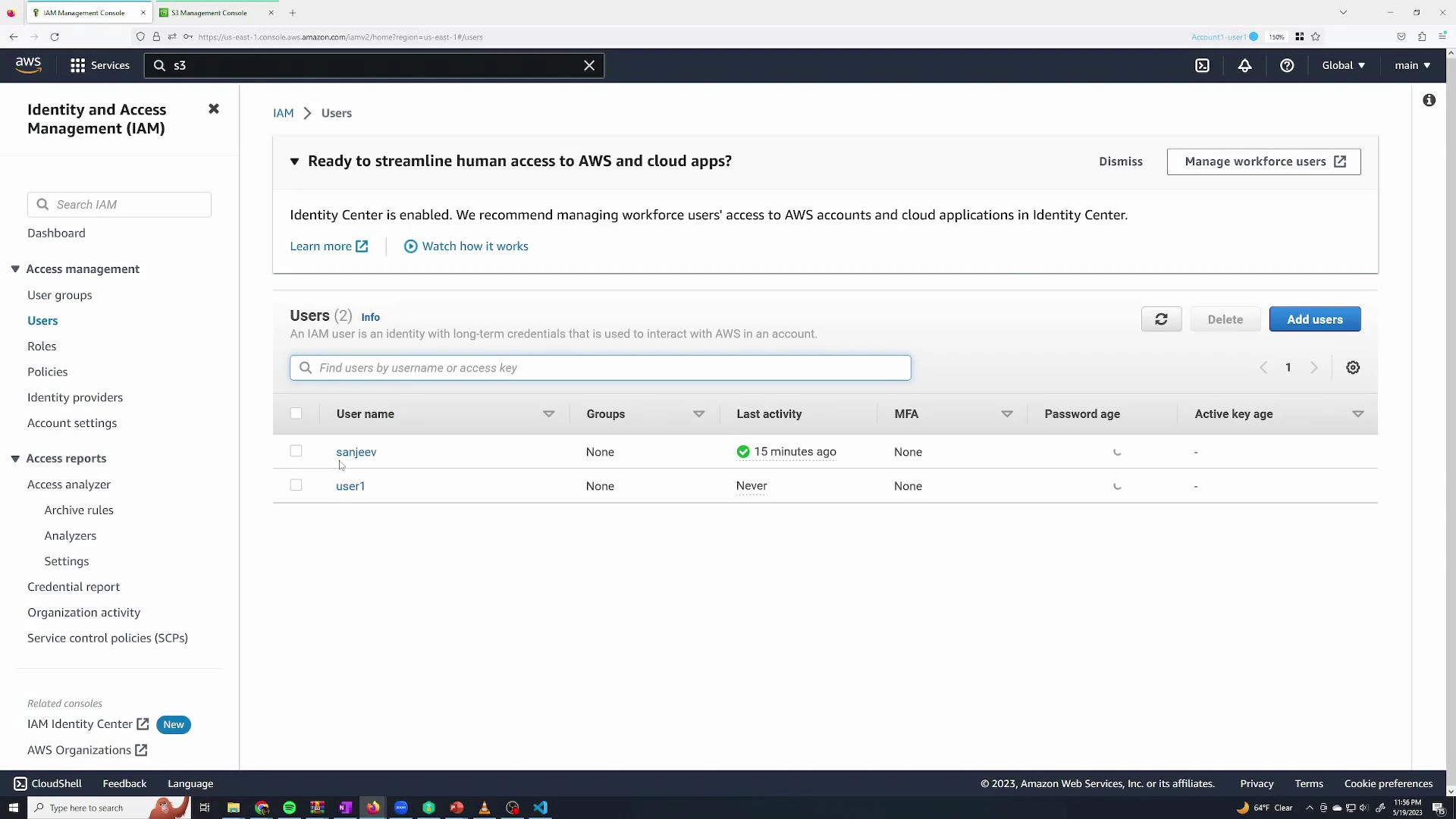 A screenshot of the AWS Identity and Access Management (IAM) console showing the Users page with two IAM accounts listed and columns for last activity, MFA, password age, and active key age. The left sidebar displays navigation items like User groups, Roles, Policies, and Access reports.