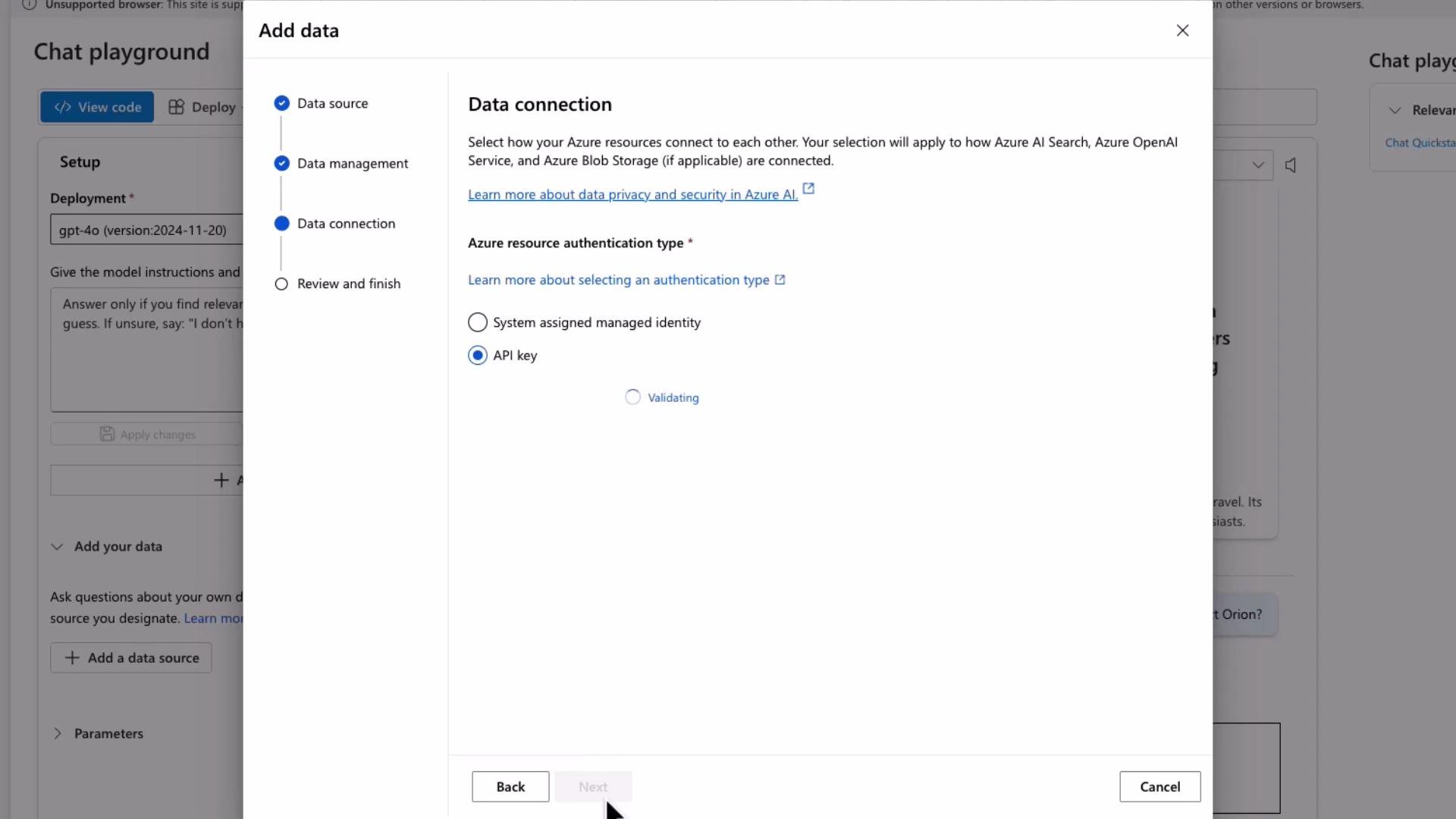 A screenshot of an "Add data" dialog in the Azure portal showing the Data connection step with "Azure resource authentication type" options, the "API key" option selected and a "Validating" status. The dialog overlays a "Chat playground" setup page in the background.