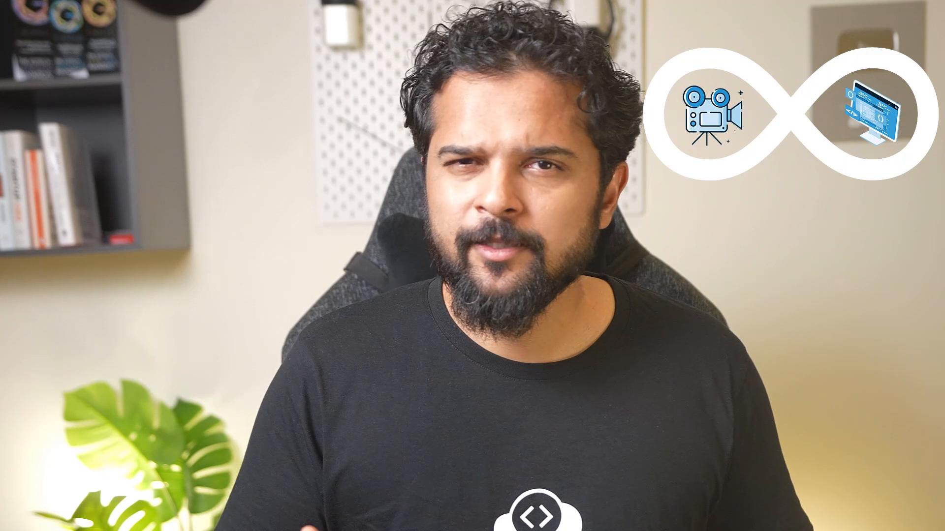 A bearded man in a black T-shirt sits in a chair in a home office or studio. To his right is an infinity-shaped graphic containing icons of a film camera and a computer monitor, with a bookshelf and plant visible behind him.