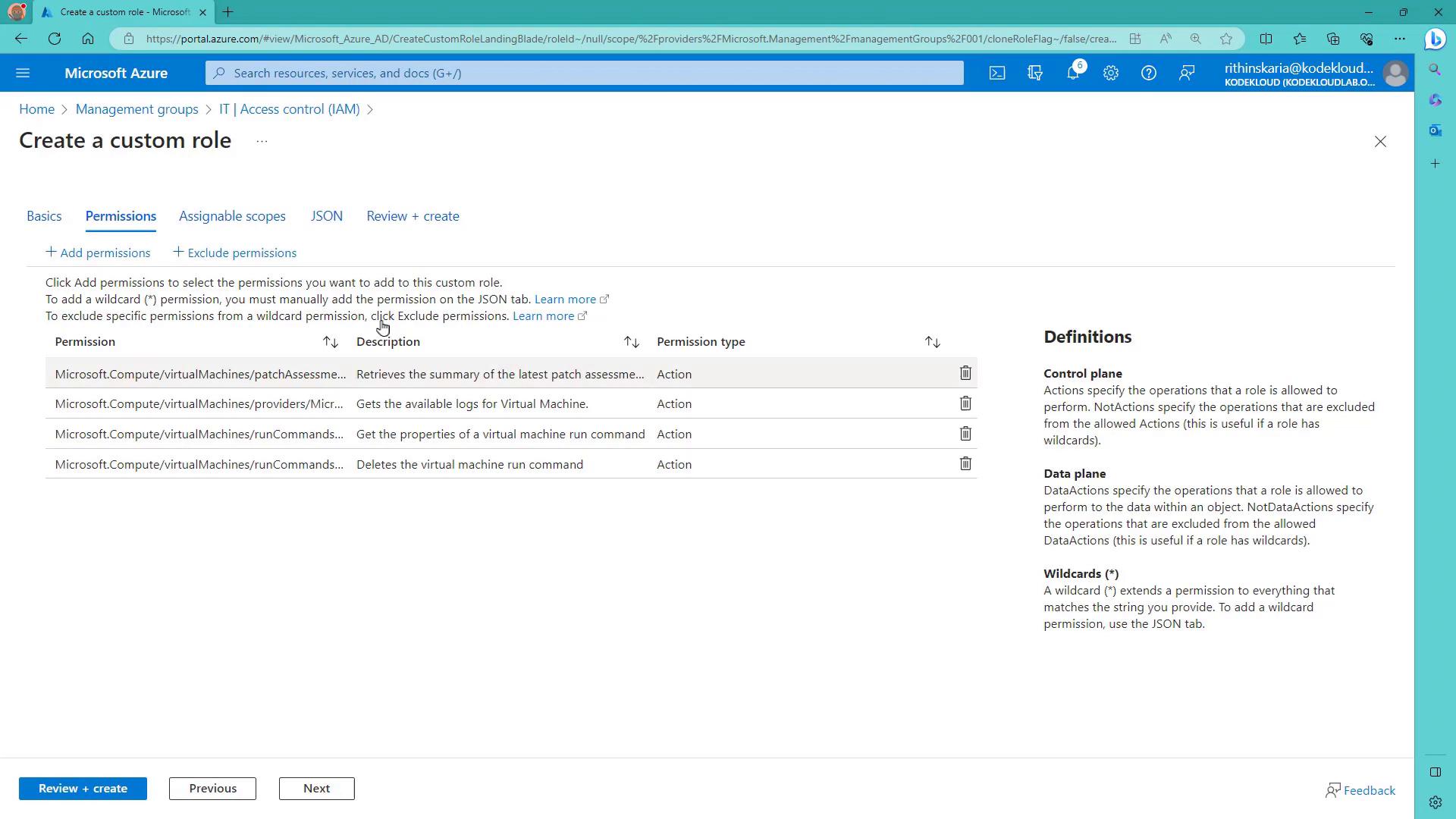 A screenshot of the Microsoft Azure portal on the "Create a custom role" page, open to the Permissions tab showing a list of virtual machine-related permissions. The right side shows a Definitions panel and navigation buttons like "Review + create," "Previous," and "Next" at the bottom.