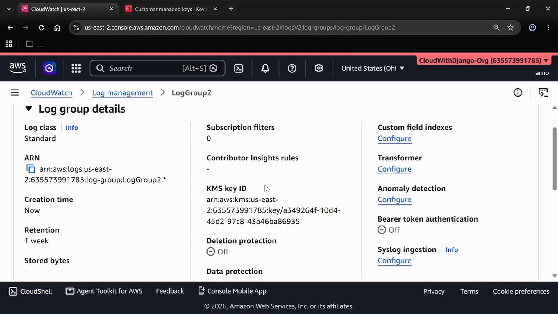 A screenshot of the AWS CloudWatch console showing the "Log group details" page for a log group (LogGroup2) with fields like ARN, retention, KMS key ID, and configuration options (transformer, anomaly detection). The browser UI and account/region bar are visible across the top.