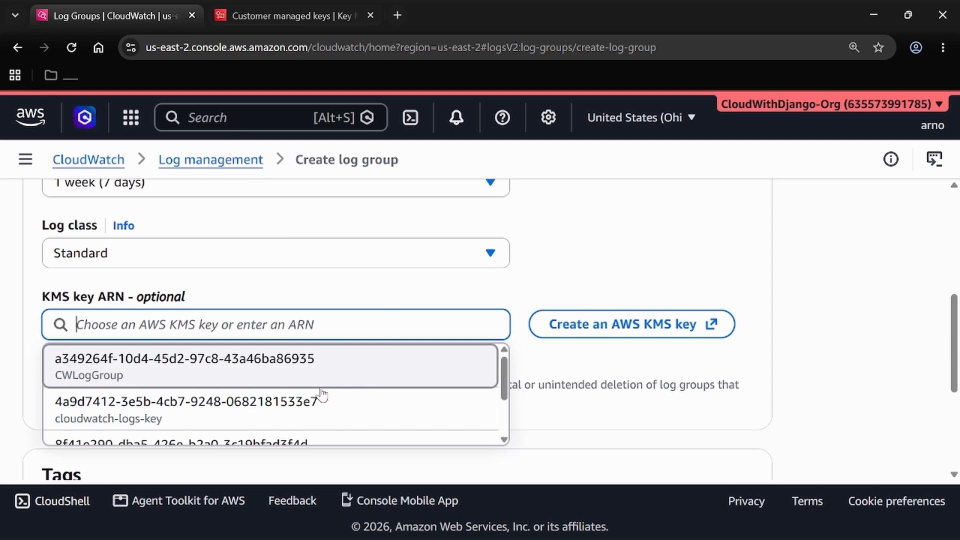 A screenshot of the AWS CloudWatch console on the "Create log group" page, showing the "KMS key ARN - optional" dropdown with several KMS key IDs listed. The page also shows options like log class set to Standard and a "Create an AWS KMS key" button.