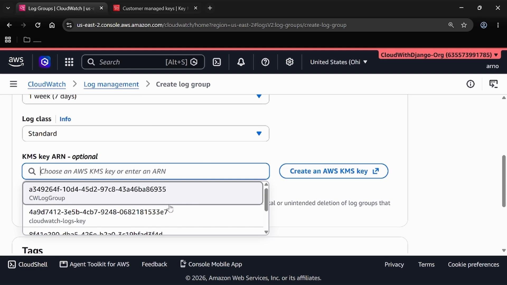A screenshot of the AWS CloudWatch console on the "Create log group" page, showing the "KMS key ARN - optional" dropdown with several KMS key IDs listed. The page also shows options like log class set to Standard and a "Create an AWS KMS key" button.