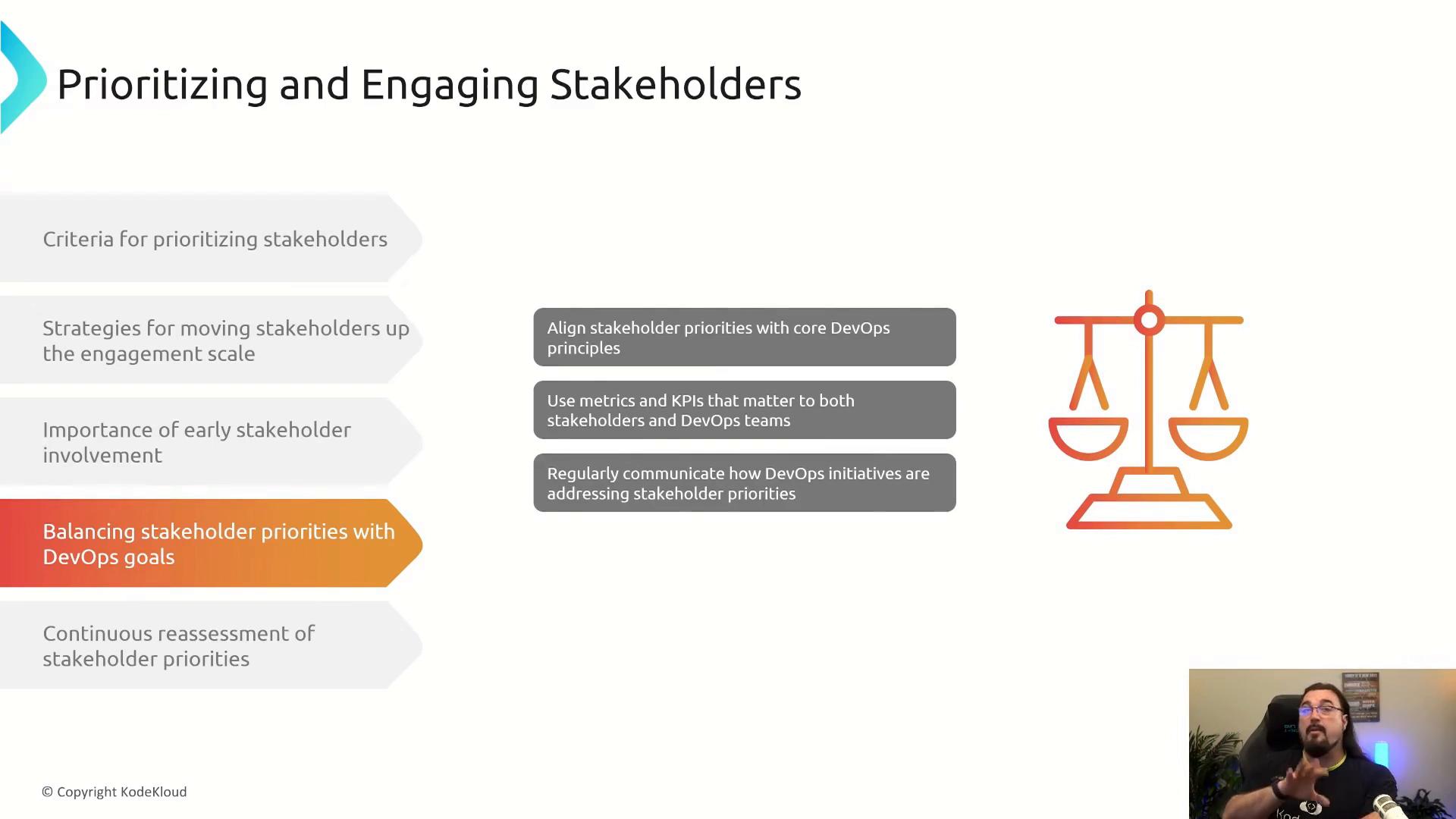 A presentation slide titled "Prioritizing and Engaging Stakeholders" showing criteria and strategies for stakeholder engagement, with a highlighted note about balancing stakeholder priorities with DevOps goals. An orange balance scale icon is on the right and a small video feed of the presenter appears in the bottom-right corner.