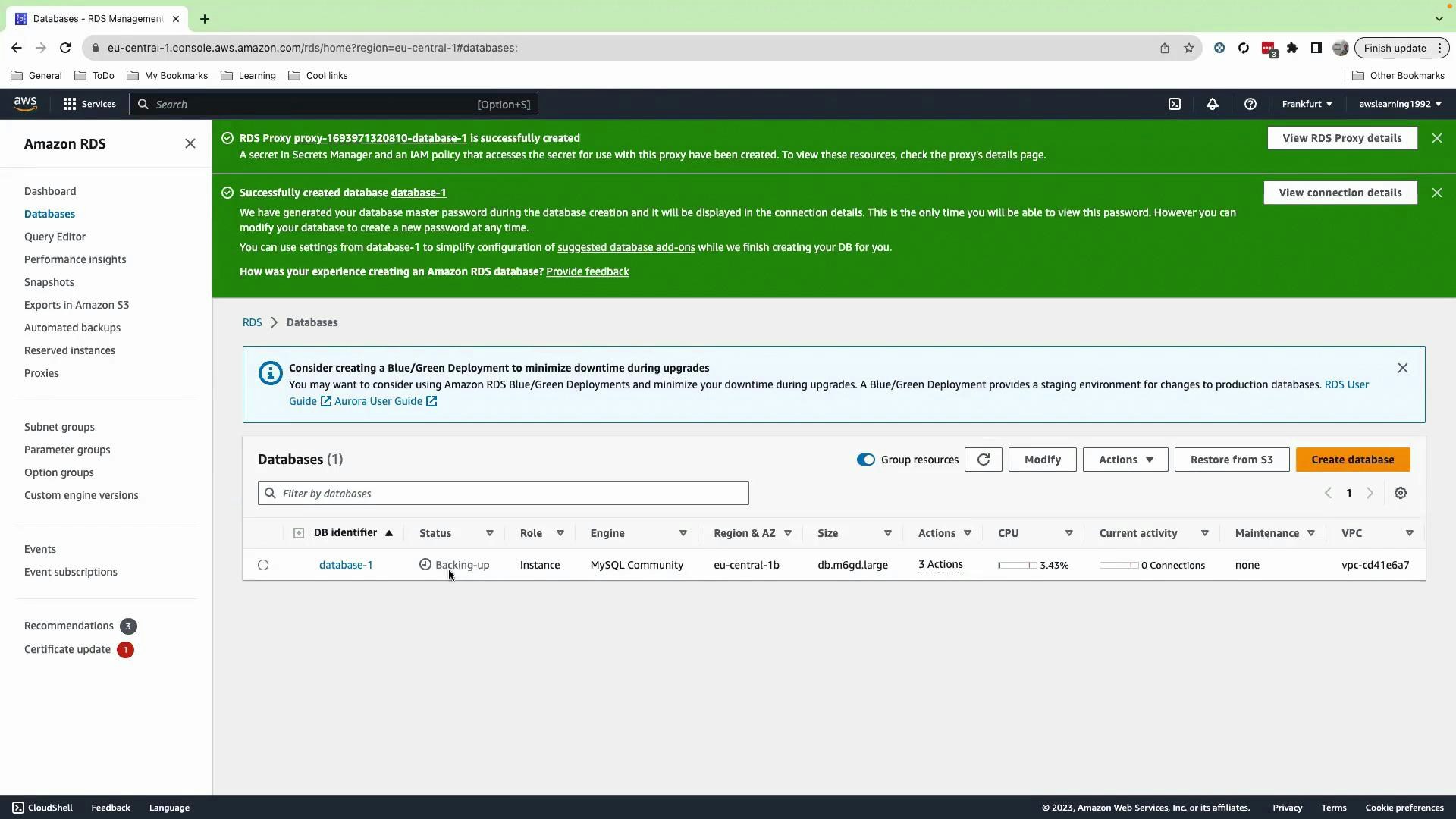 A screenshot of the Amazon RDS management console showing success banners and a Databases view. The database list shows a single instance named "database-1" with status "Backing‑up" and engine MySQL Community.