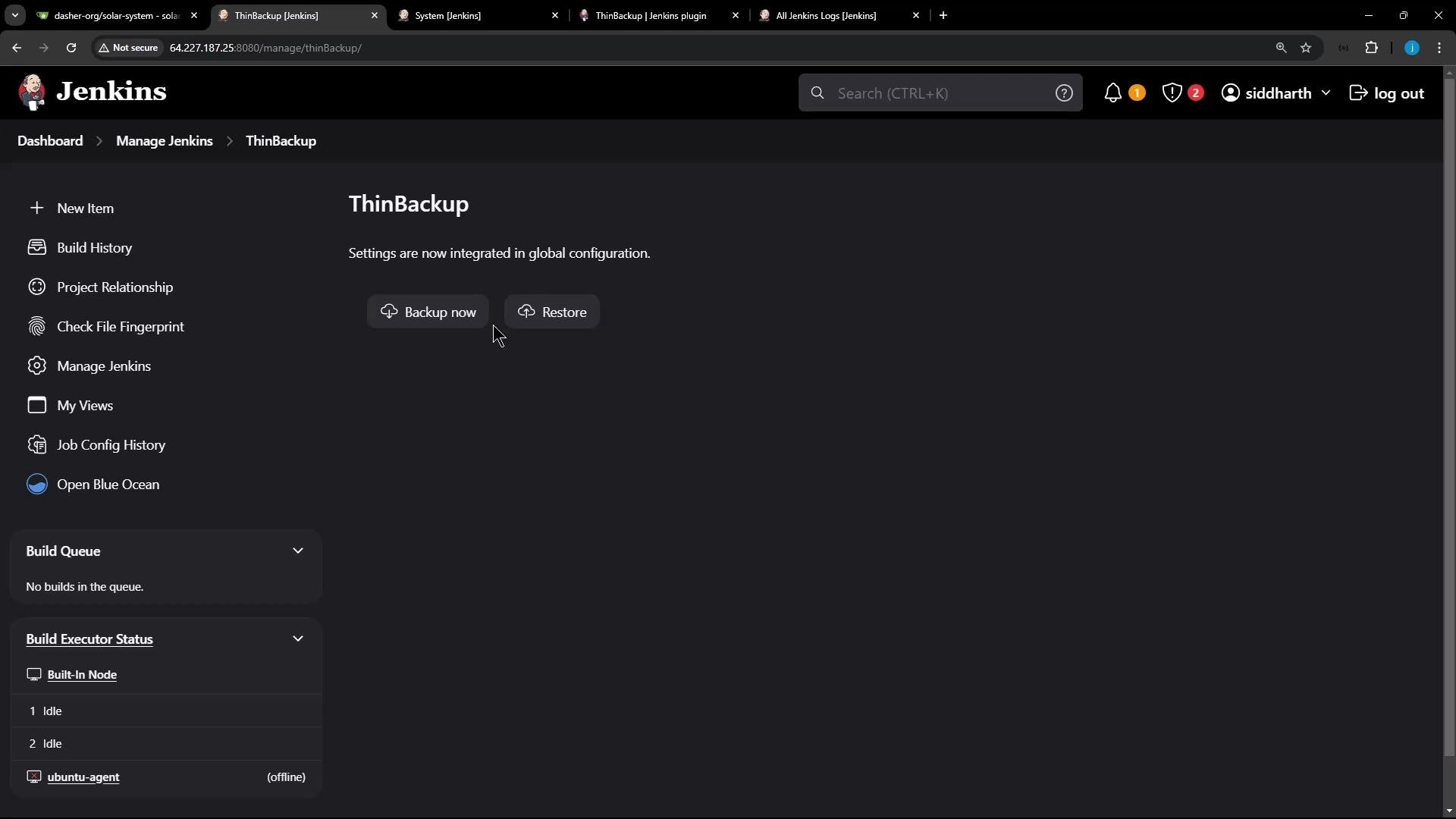 A screenshot of the Jenkins web UI on the ThinBackup plugin page, with prominent "Backup now" and "Restore" buttons in the center. The dark-themed layout shows the Jenkins logo and a left navigation panel with items like Build History, Manage Jenkins, and Build Executor Status.