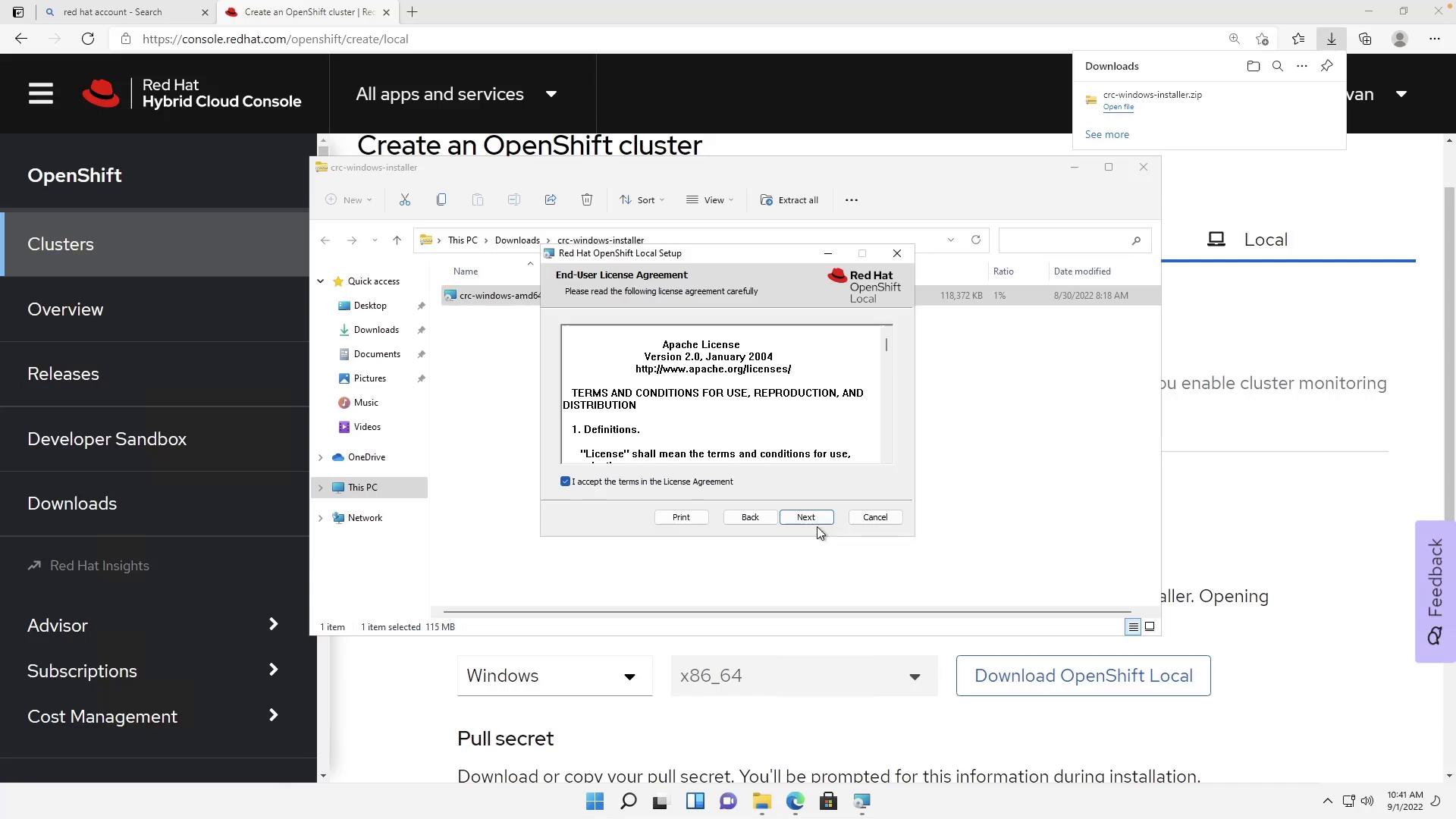 A screenshot of the Red Hat Hybrid Cloud Console "Create an OpenShift cluster" page with a Windows File Explorer window open and the Red Hat OpenShift Local installer displaying an End-User License Agreement dialog. The installer shows the Apache License text with the "I accept" checkbox checked and the Next button highlighted.