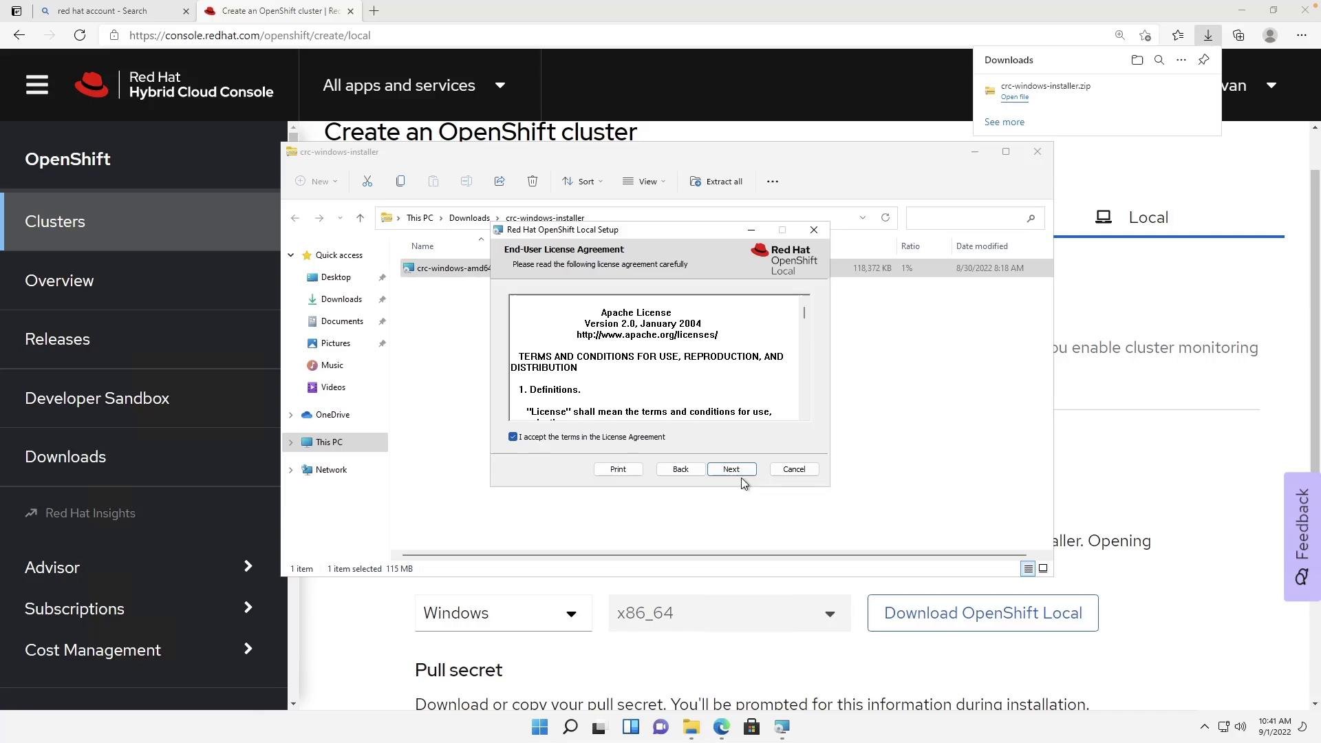 A screenshot of the Red Hat Hybrid Cloud Console "Create an OpenShift cluster" page with a Windows File Explorer window open and the Red Hat OpenShift Local installer displaying an End-User License Agreement dialog. The installer shows the Apache License text with the "I accept" checkbox checked and the Next button highlighted.