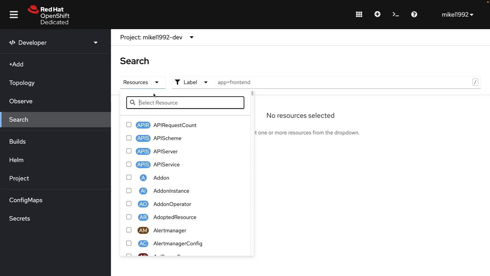 A screenshot of the Red Hat OpenShift Dedicated developer console showing the Search page for project "mikel1992-dev" with the Resources dropdown expanded, listing resource types like APIRequestCount, APIScheme, APIServer, and more. The sidebar navigation is visible and a label filter "app=frontend" is applied while the main pane reads "No resources selected."