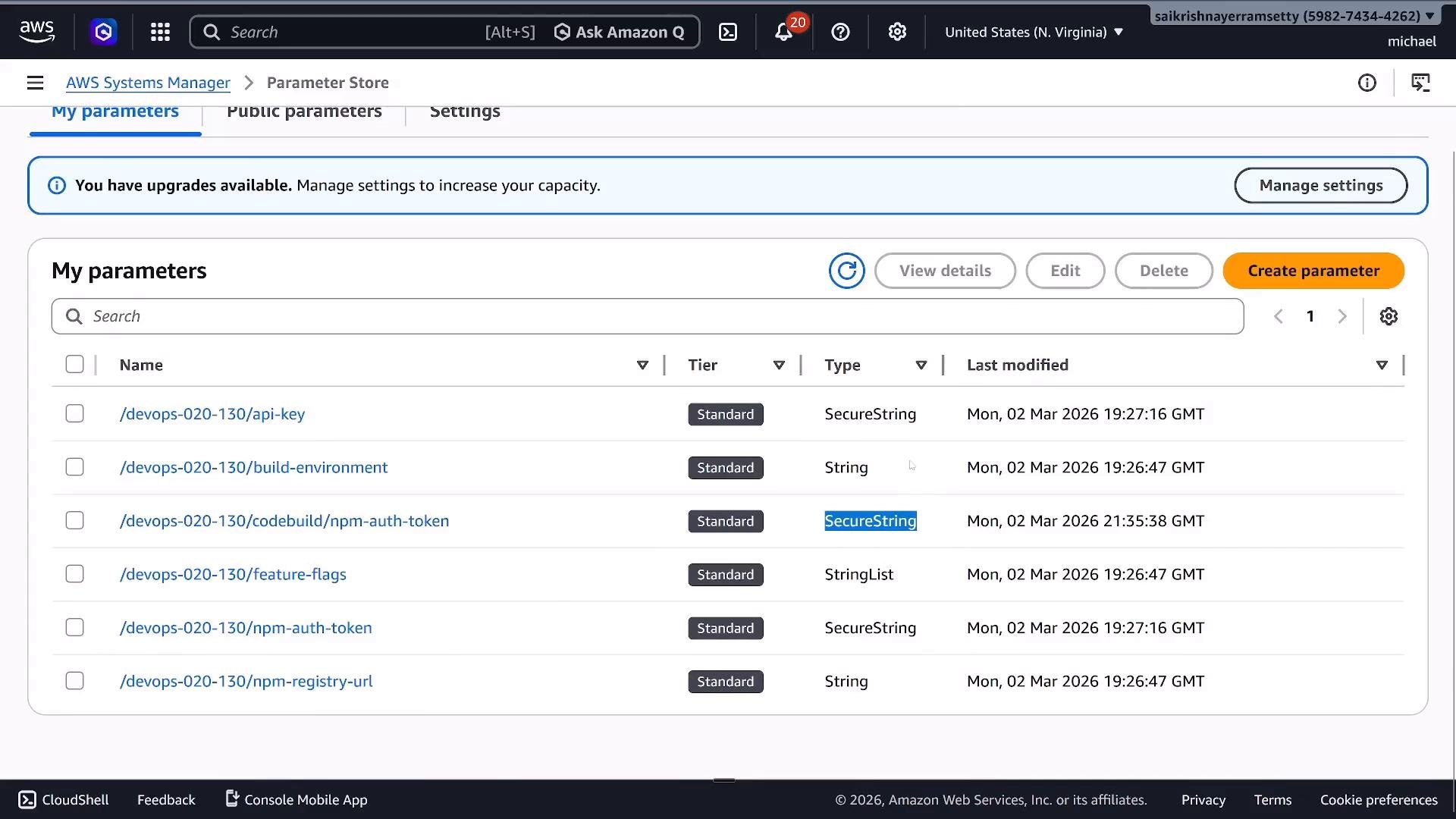 Screenshot of the AWS Systems Manager Parameter Store console listing parameters (e.g., /devops-020-130/api-key, build-environment, npm-auth-token) with their tiers, types (SecureString, String, StringList) and last-modified timestamps. The top bar shows a notification about available upgrades and a "Create parameter" button.