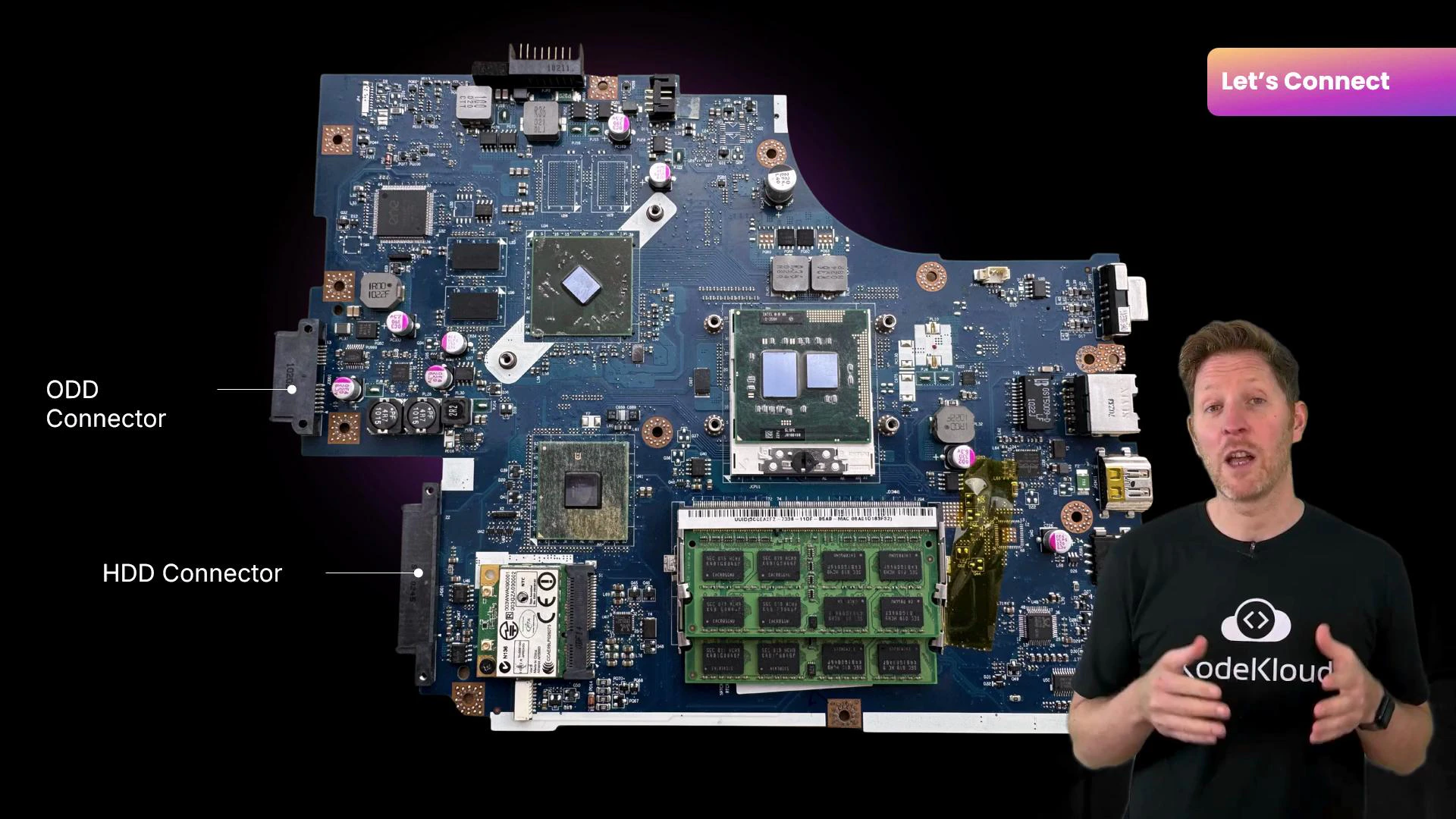 A laptop motherboard shown close-up with RAM sticks, chips, and labeled ODD and HDD connectors. A presenter stands to the right, gesturing as if explaining the board.