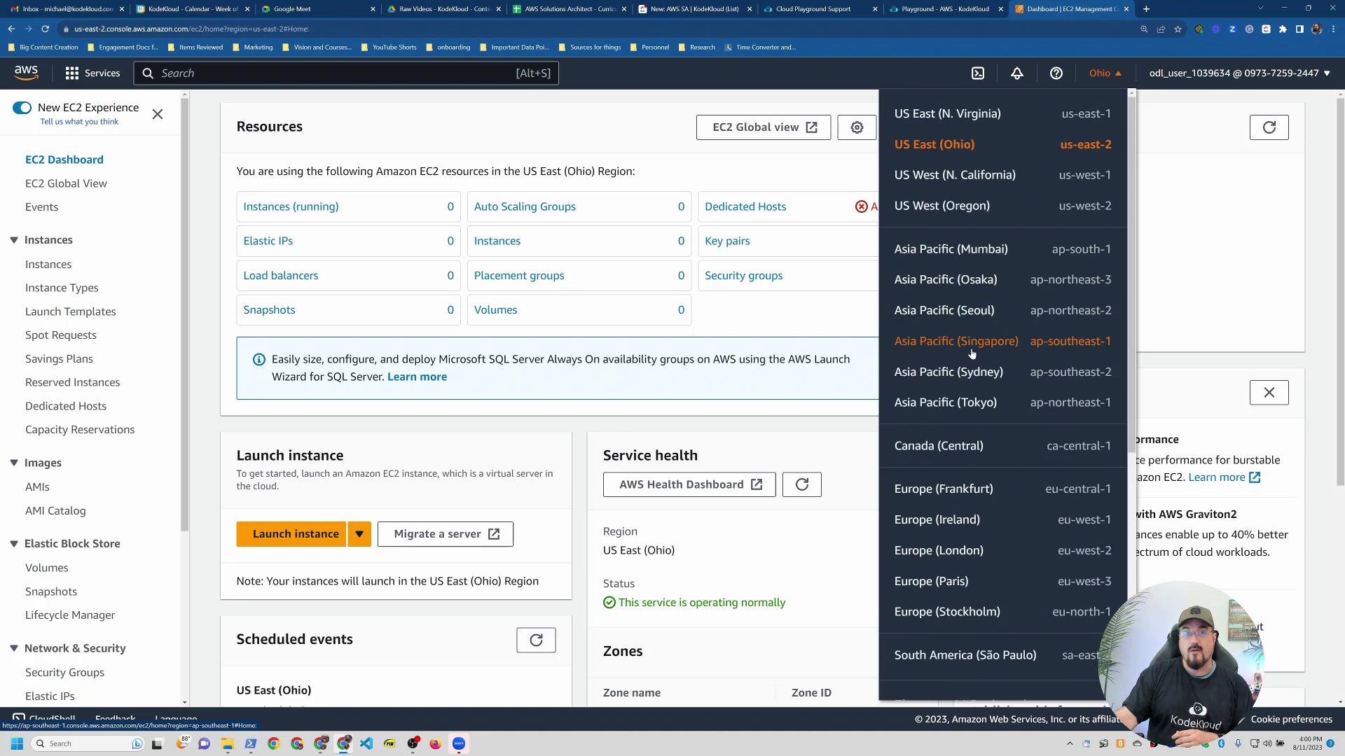 A screenshot of the AWS EC2 console showing the Resources/Launch instance panels with the region selector open (listing regions like US East and Asia Pacific). A small circular webcam overlay of a person appears in the bottom-right.