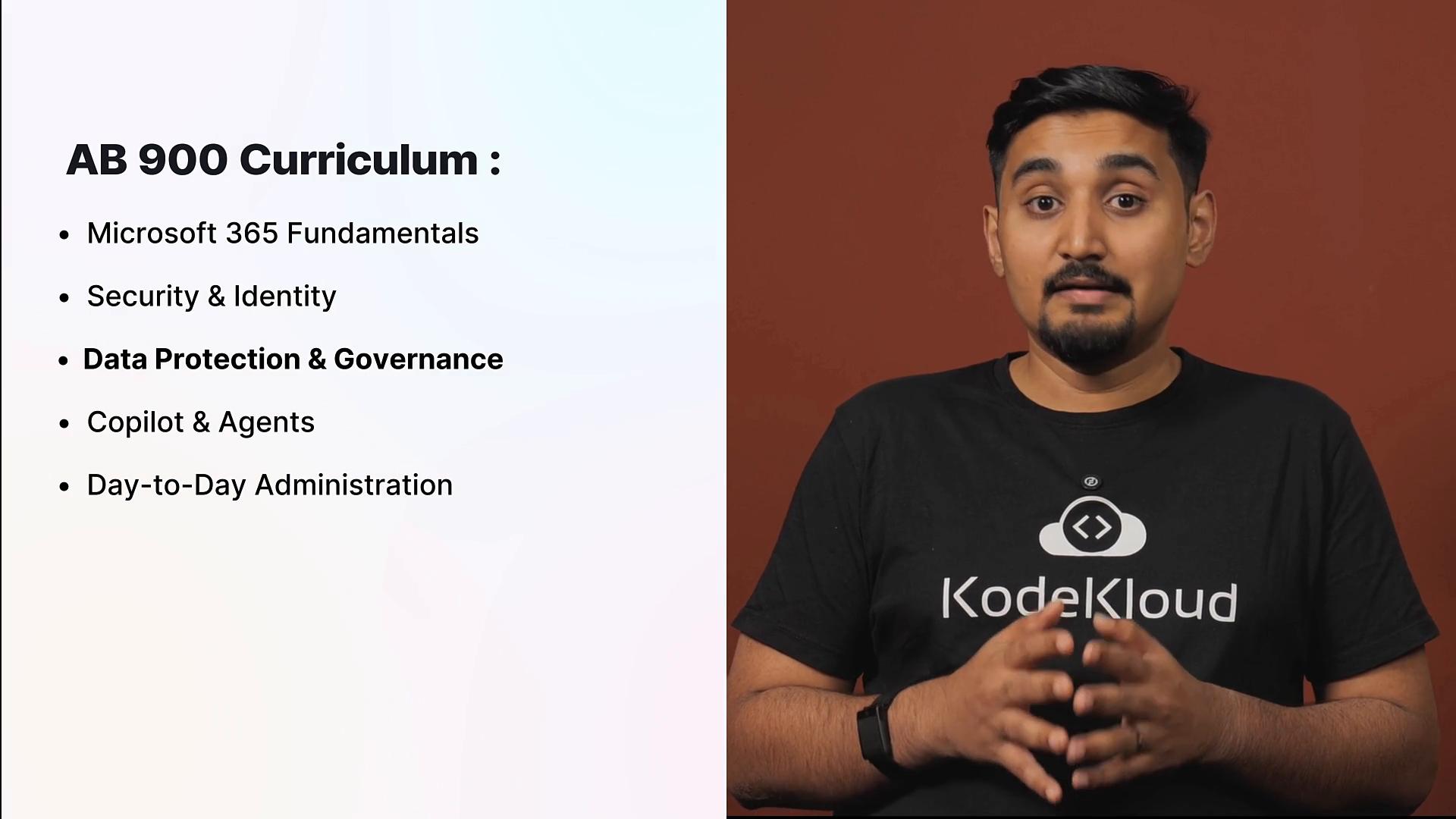 A presenter wearing a KodeKloud T‑shirt speaks against a brown background. Beside him a slide titled "AB 900 Curriculum" lists topics like Microsoft 365 Fundamentals, Security & Identity, Data Protection & Governance, Copilot & Agents, and Day‑to‑Day Administration.