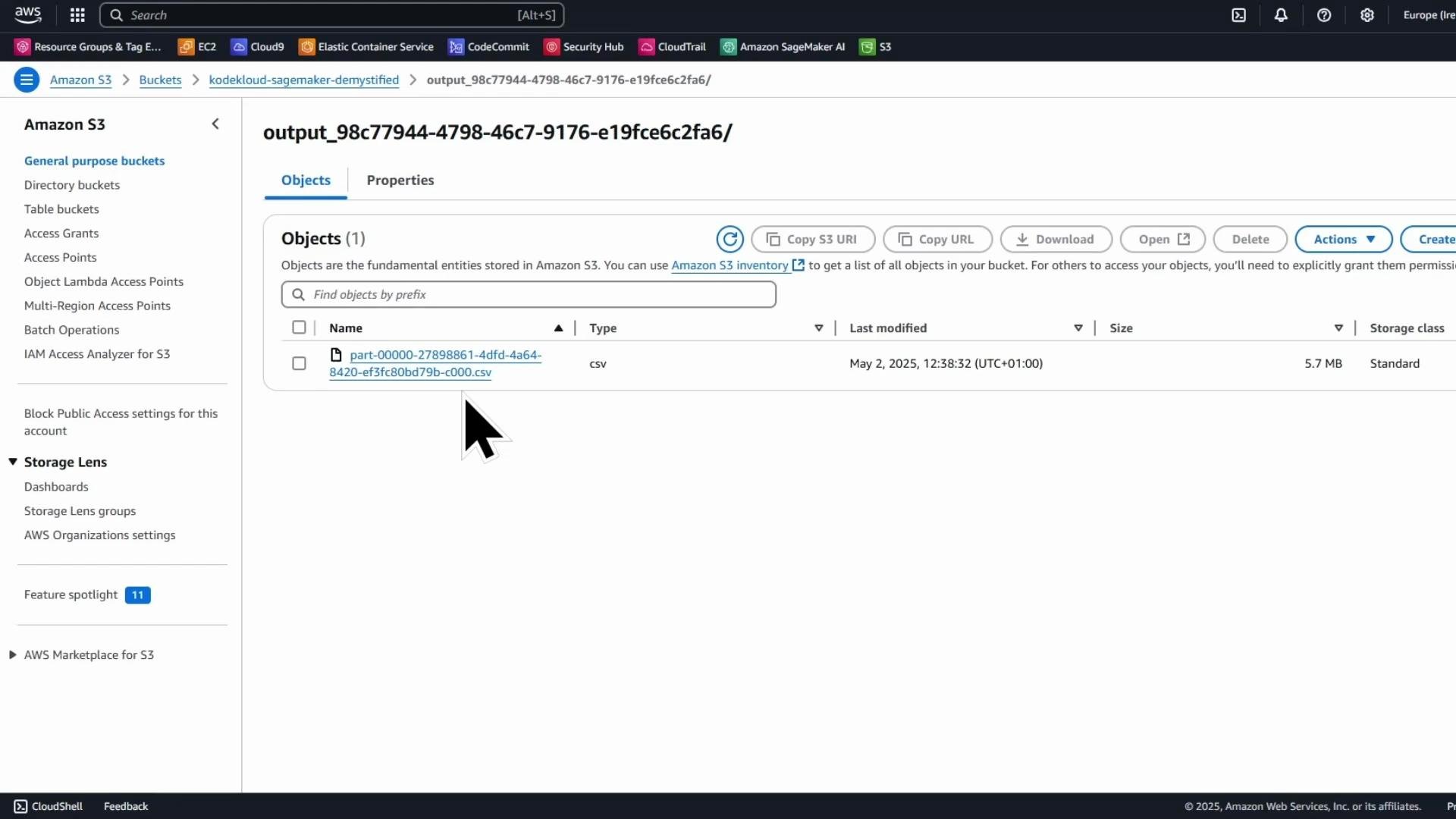 A screenshot of the Amazon S3 web console showing the contents of a folder (output_98c77944-4798-46c7-9176-e19fce6c2fa6/) with a single CSV object named "part-00000-27898861-4dfd-4a64-8420-ef3fc80bd79b-c000.csv". The file is 5.7 MB and was last modified on May 2, 2025, with the cursor hovering over the filename.