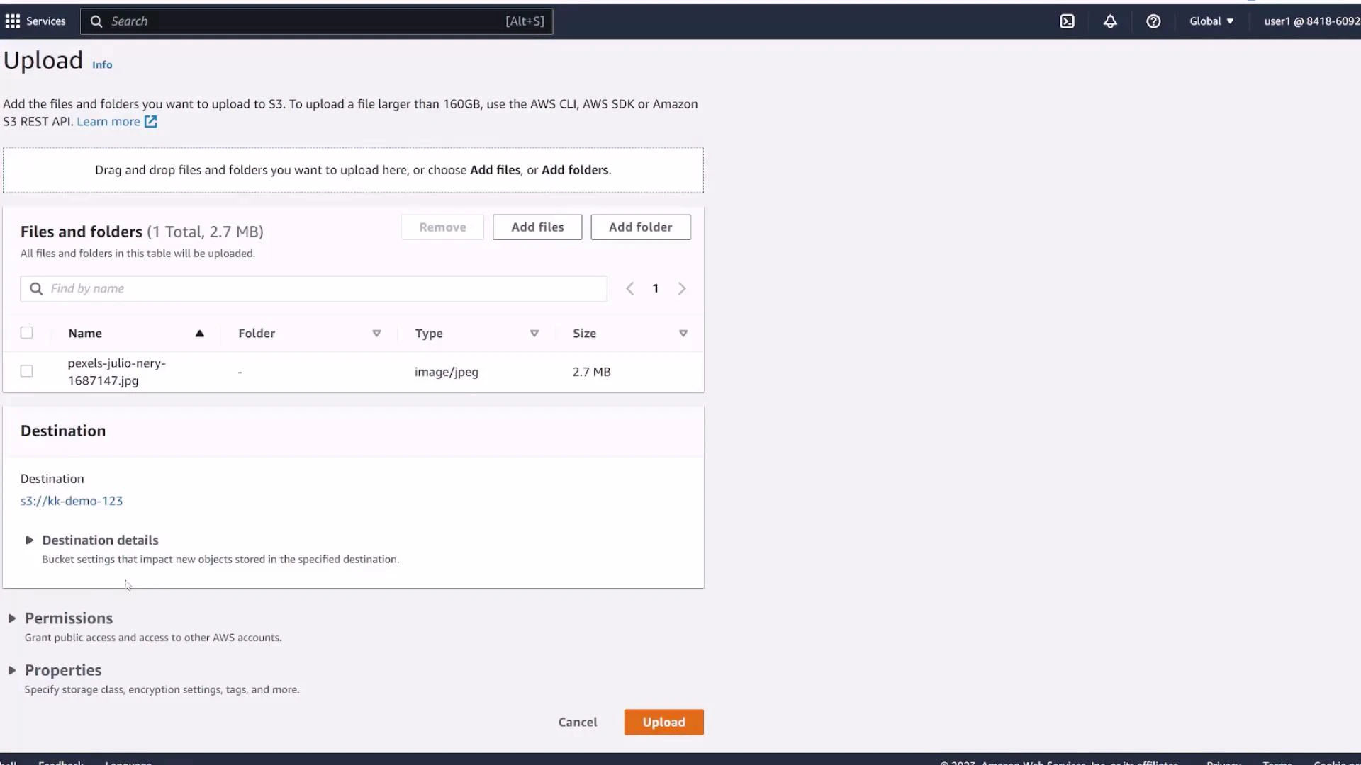 A screenshot of the AWS S3 "Upload" page showing one JPEG file (pexels-julio-nery-1687147.jpg, 2.7 MB) queued for upload. The destination bucket is s3://kk-demo-123 and there are Cancel and Upload buttons at the bottom.