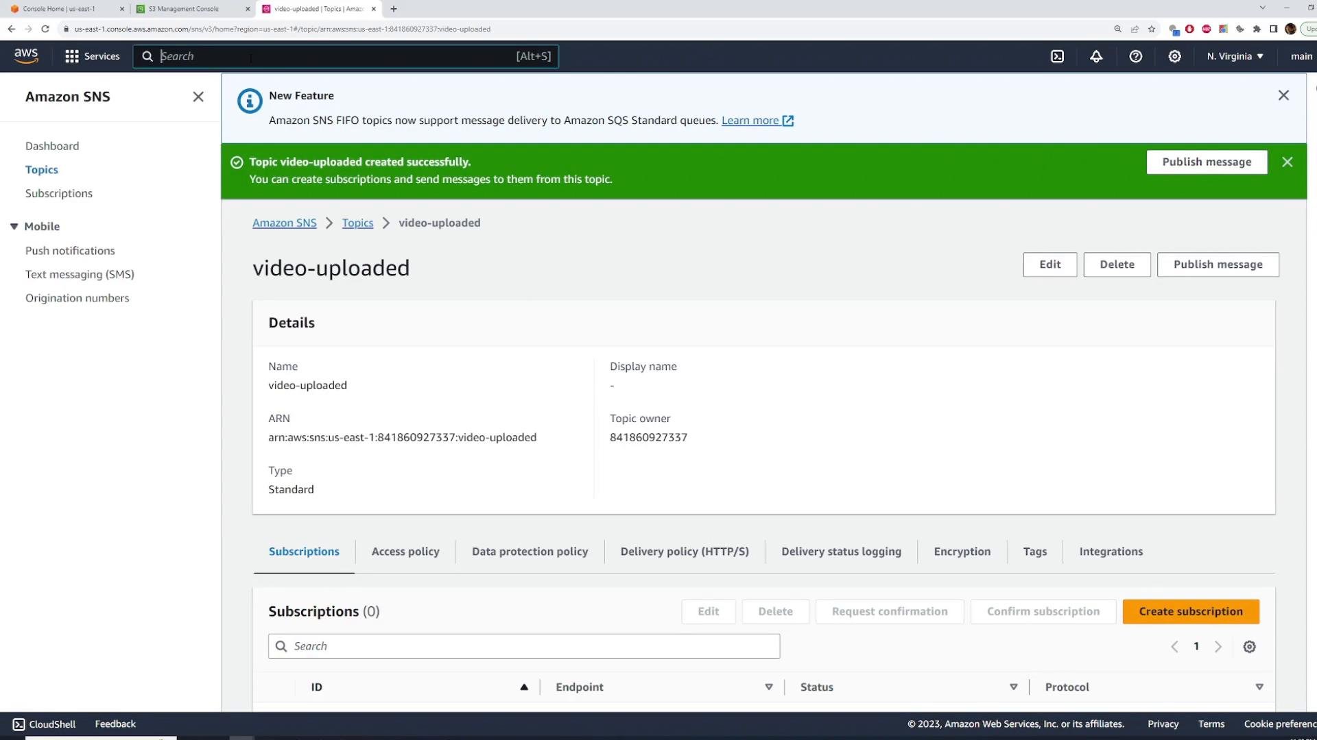 A screenshot of the AWS Amazon SNS console showing a "video-uploaded" topic with a green banner confirming the topic was created. The page shows the topic details (name, ARN, owner), action buttons (Edit, Delete, Publish message) and sections for subscriptions and policies.
