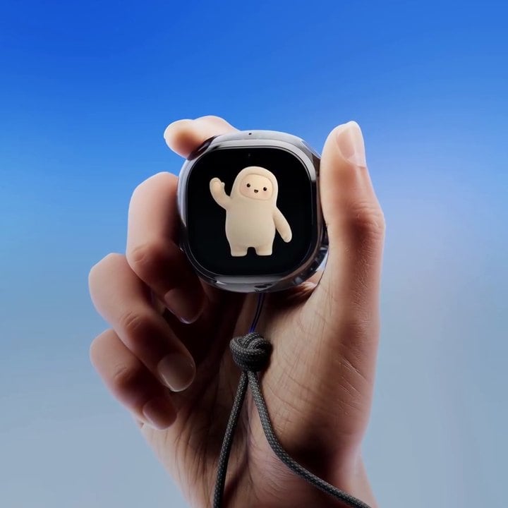 A hand holding Meta's Muse Charm device, with the Muse character waving on its screen