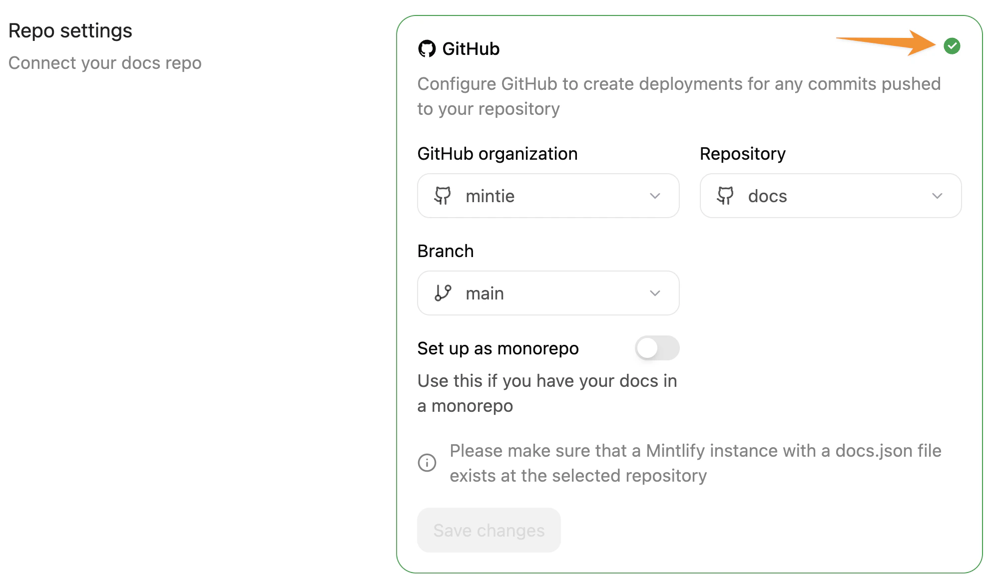 Mintlify 控制台中的 Git Settings 页面。橙色箭头指向用于重新验证存储库设置的绿色勾选图标。