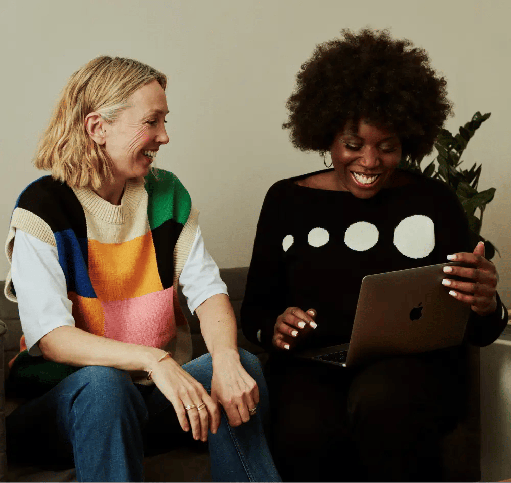 Two colleagues sharing a smile while working together on a laptop.