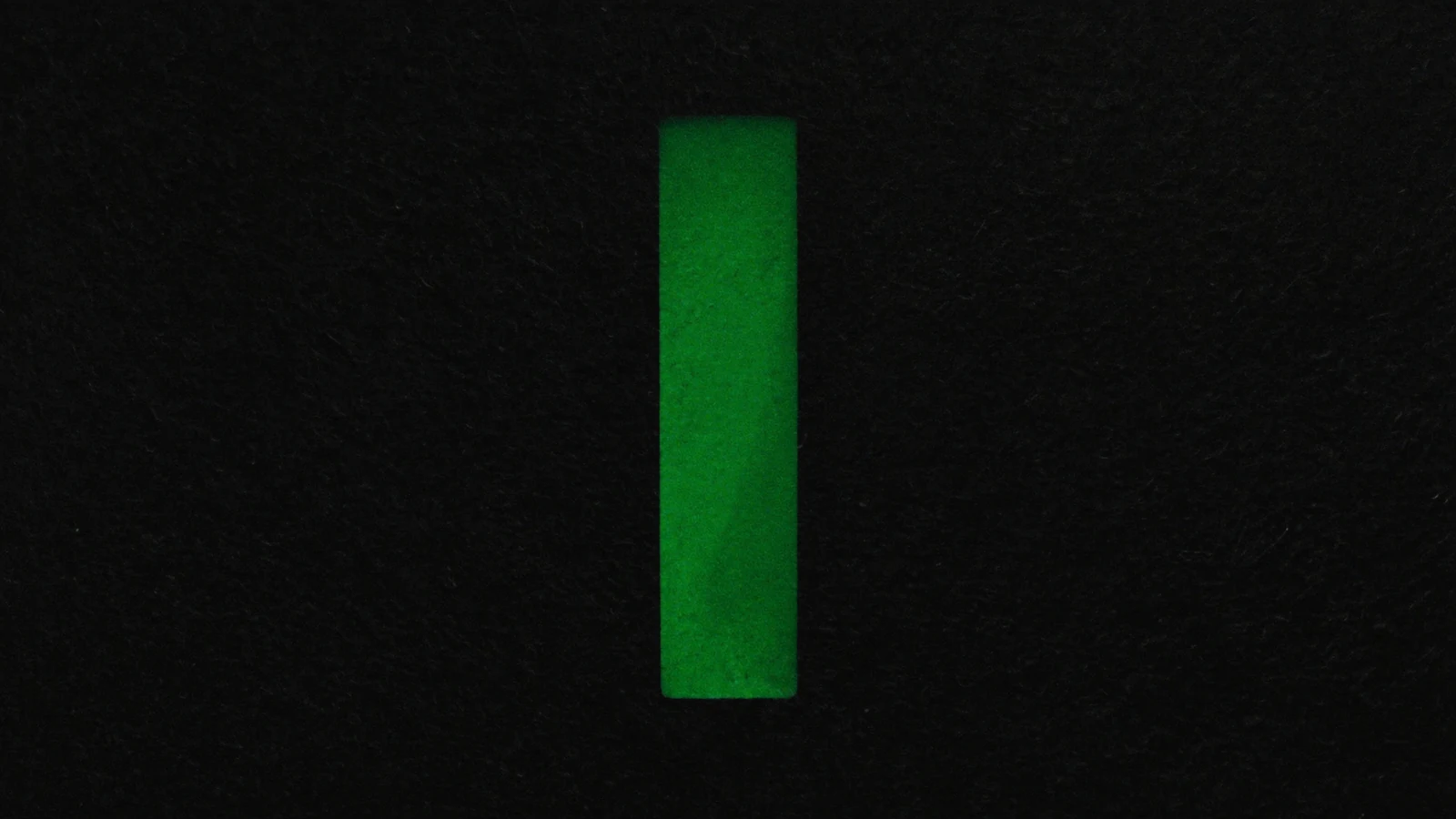 A narrow, tall vertical rectangle of green light on a black background