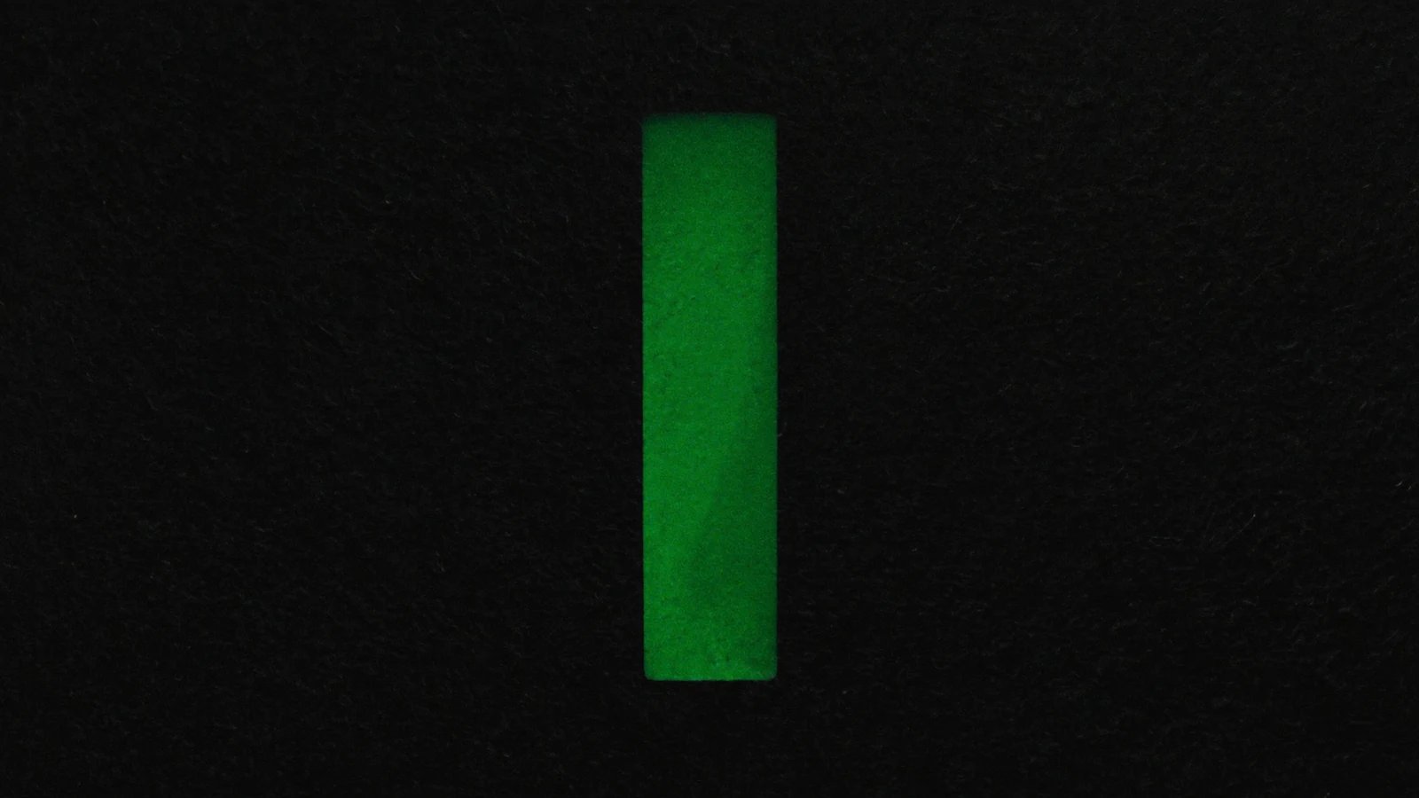 A narrow, tall vertical rectangle of green light on a black background