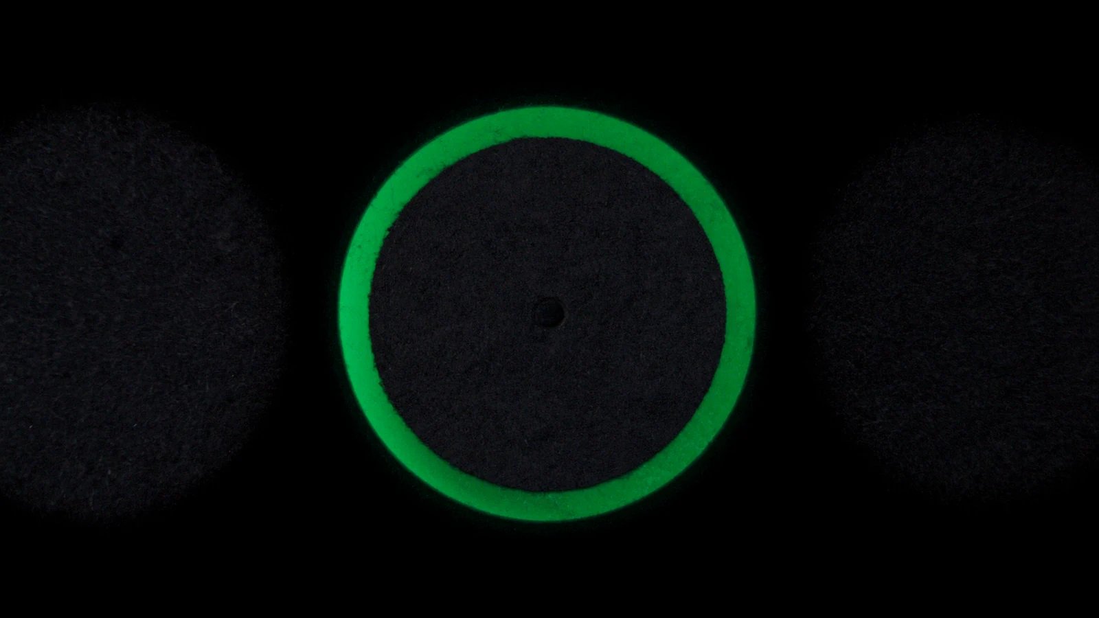 Plusieurs disques mats posés à plat sur un fond sombre, un seul cerné de vert