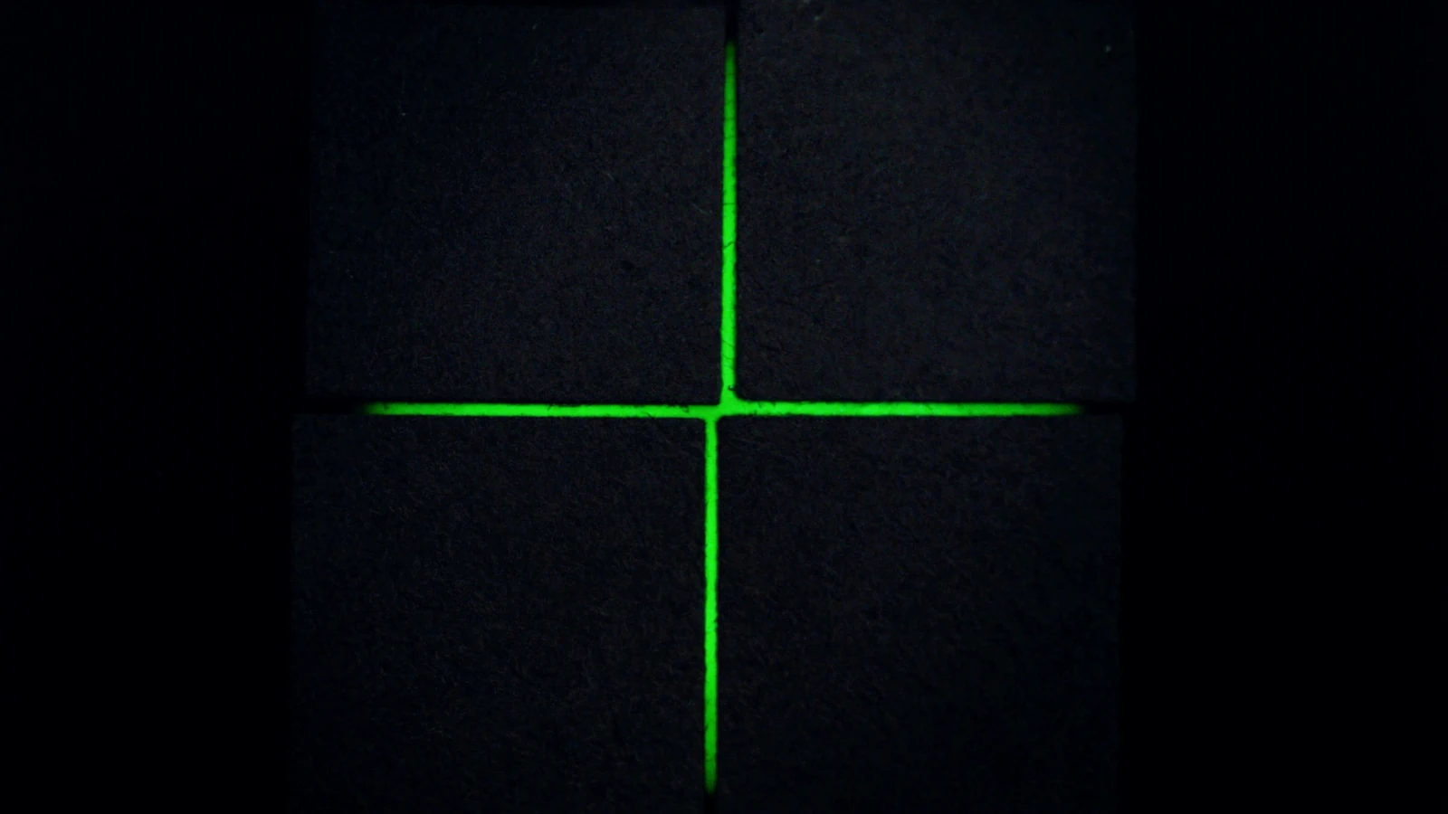Two green lines joining at a right angle at the centre of a matte surface