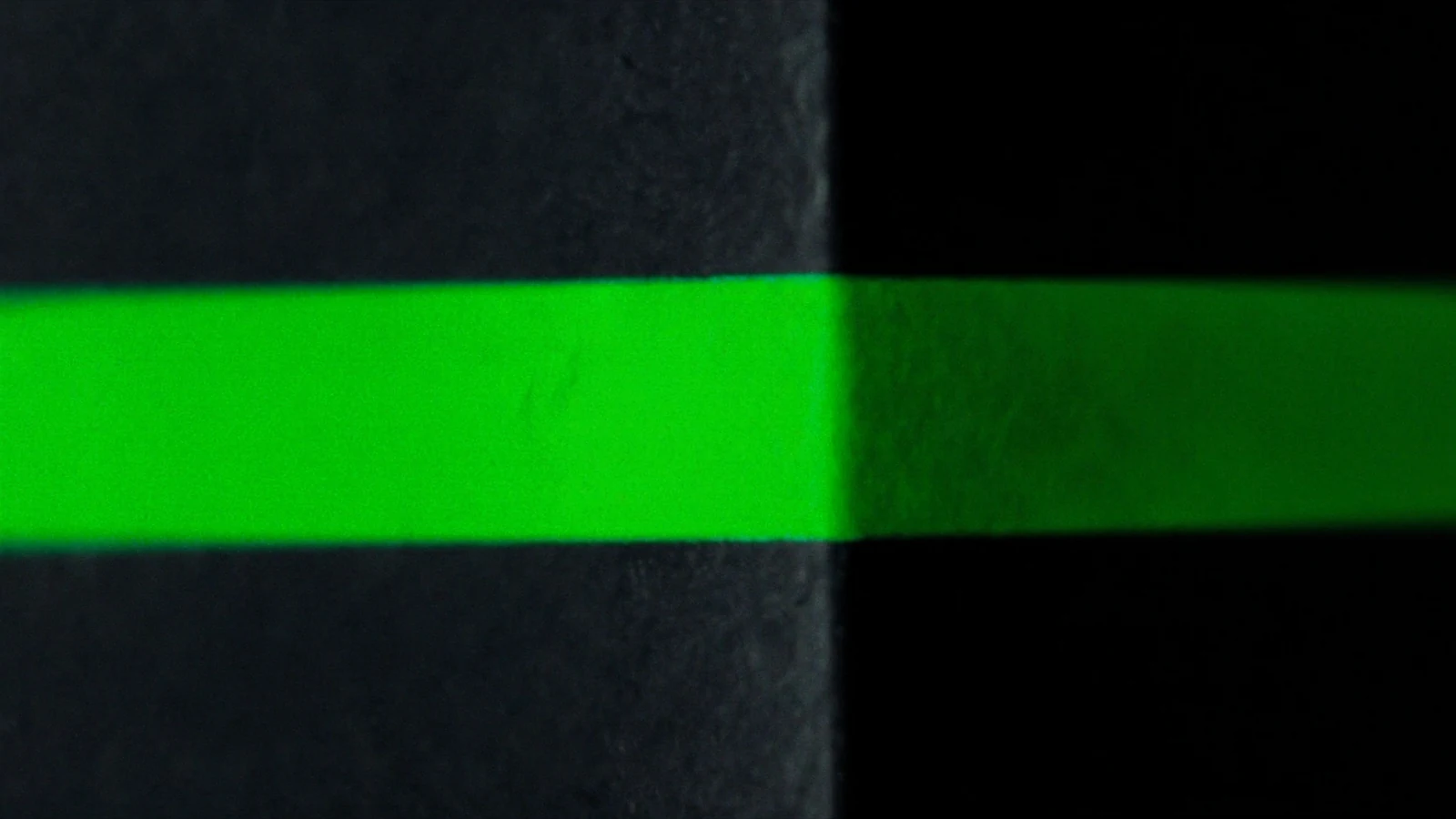 A matt cube belted by a single band of green light