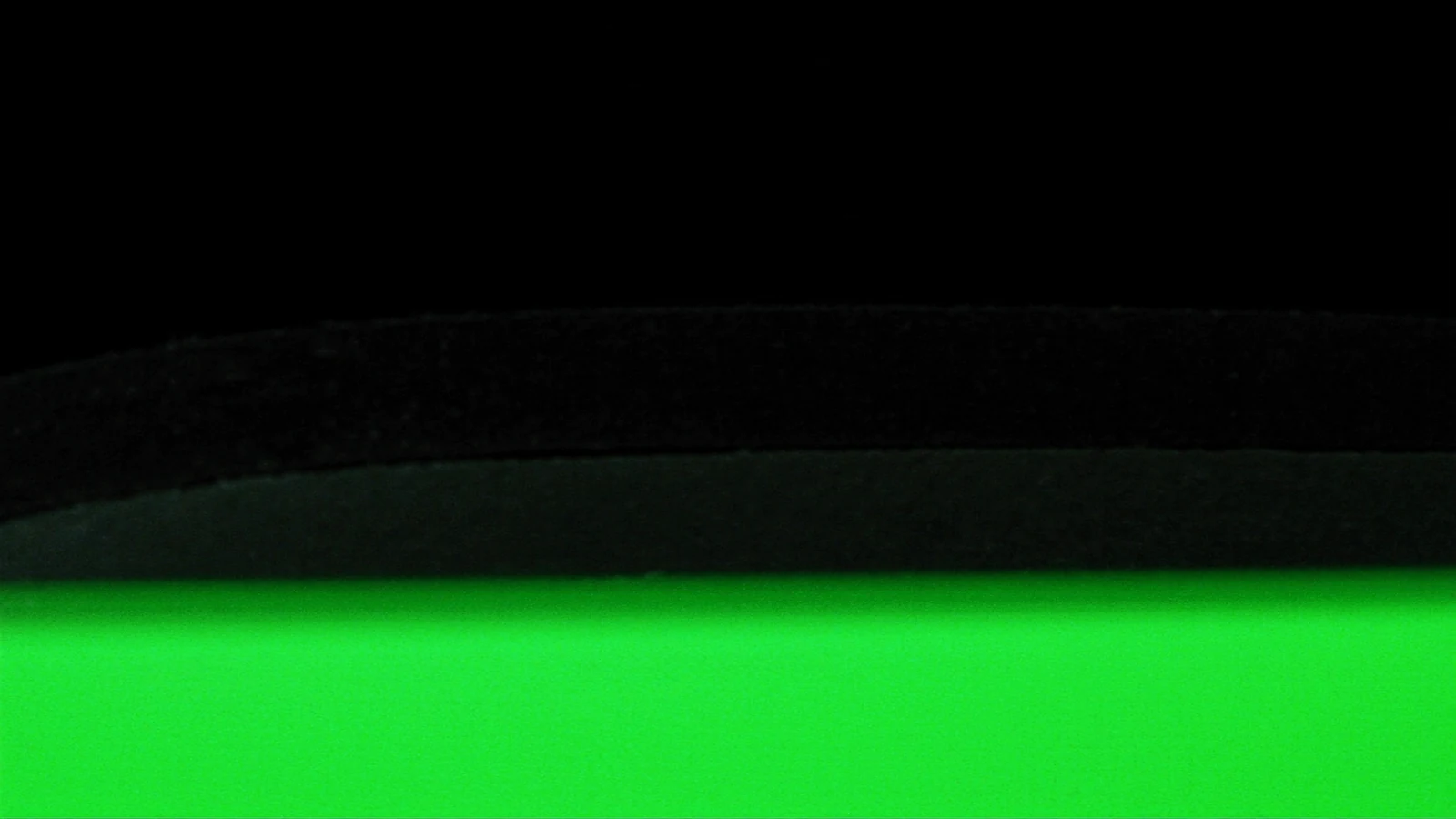 A sharp horizontal green line under a stack of matte blocks on a black background