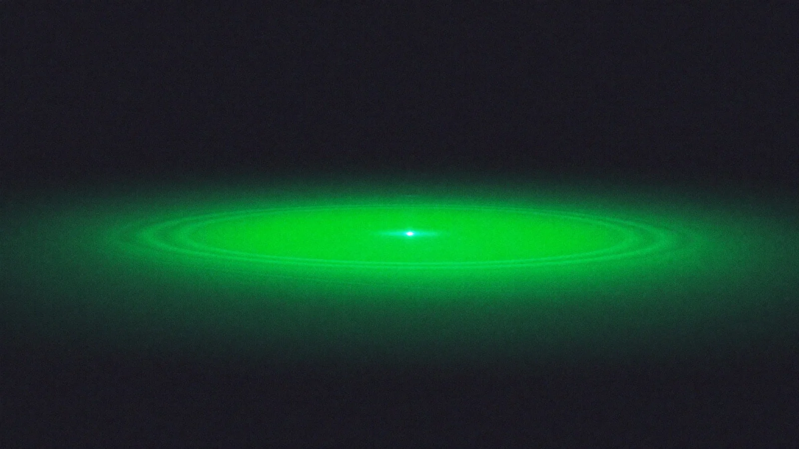 A wide flat ellipse of green light spreading from a bright point on a dark background