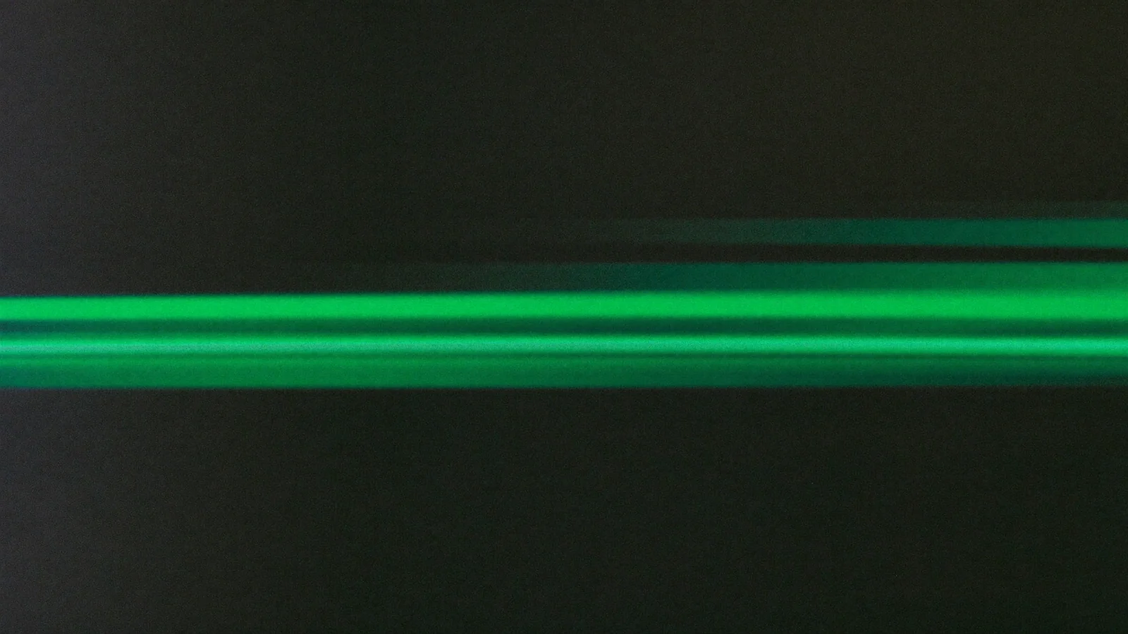 Two horizontal green streaks of light on a dark background, one ahead of the other