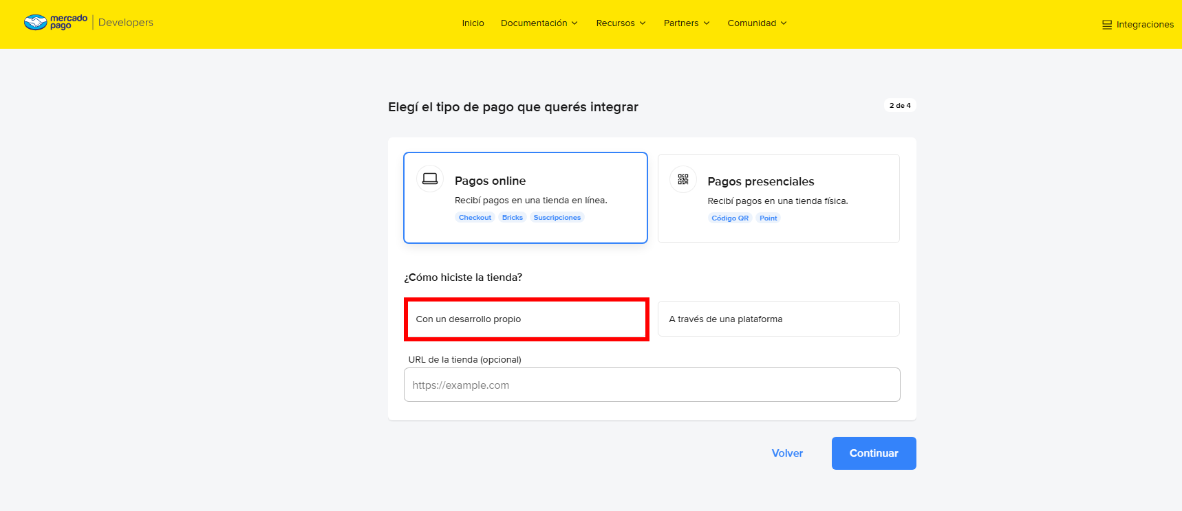 O mesmo passo com «Pagos online» já selecionado. Um retângulo vermelho destaca a opção «Con un desarrollo propio» sob a pergunta «¿Cómo hiciste la tienda?», com o campo opcional «URL de la tienda» abaixo.