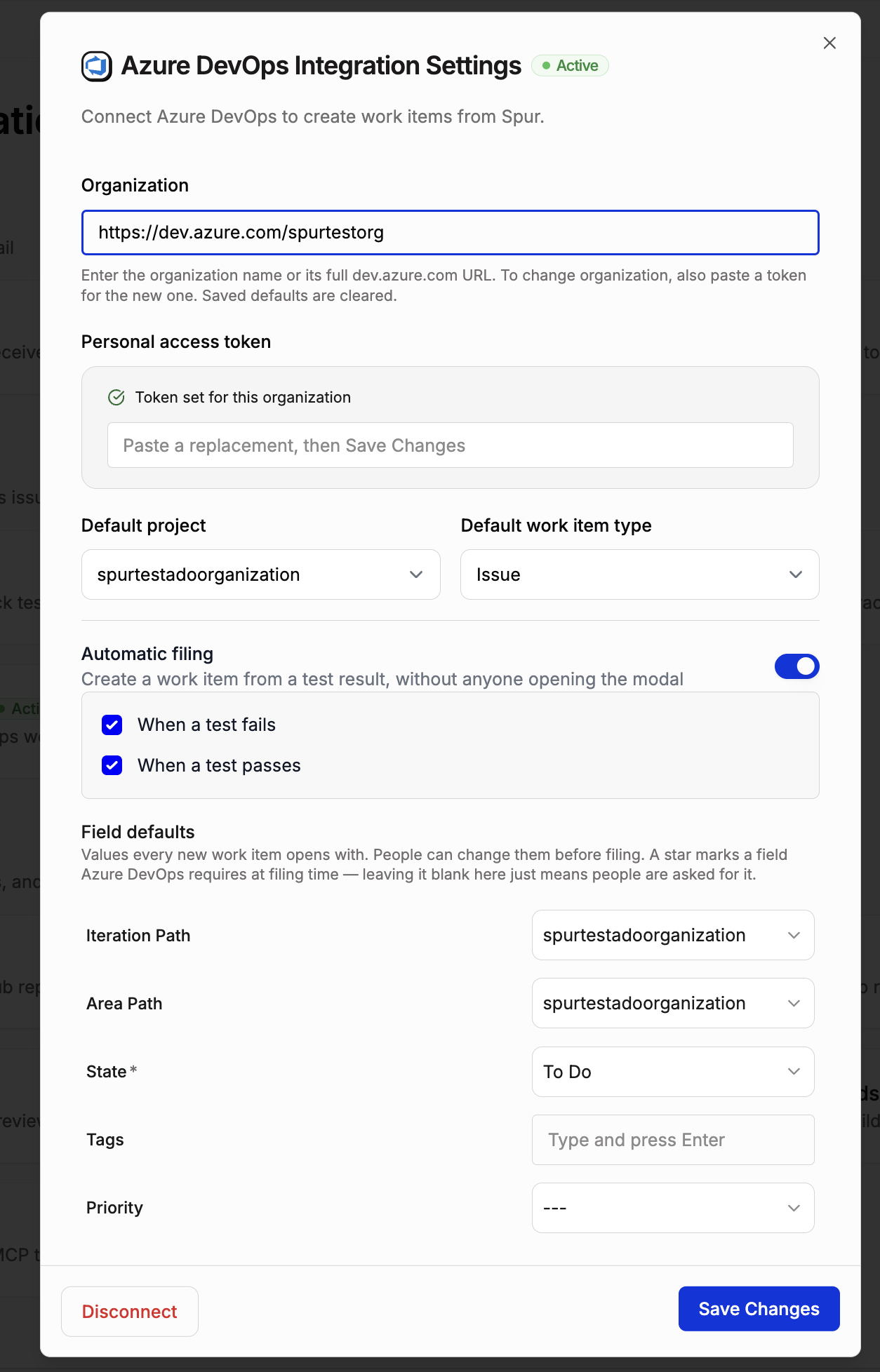 Azure DevOps Integration Settings dialog marked Active, showing an Organization field set to a dev.azure.com URL, a personal access token field reading "Token set for this organization", Default project and Default work item type dropdowns, an Automatic filing toggle with "When a test fails" and "When a test passes" both checked, and a Field defaults list of Iteration Path, Area Path, State, Tags, and Priority