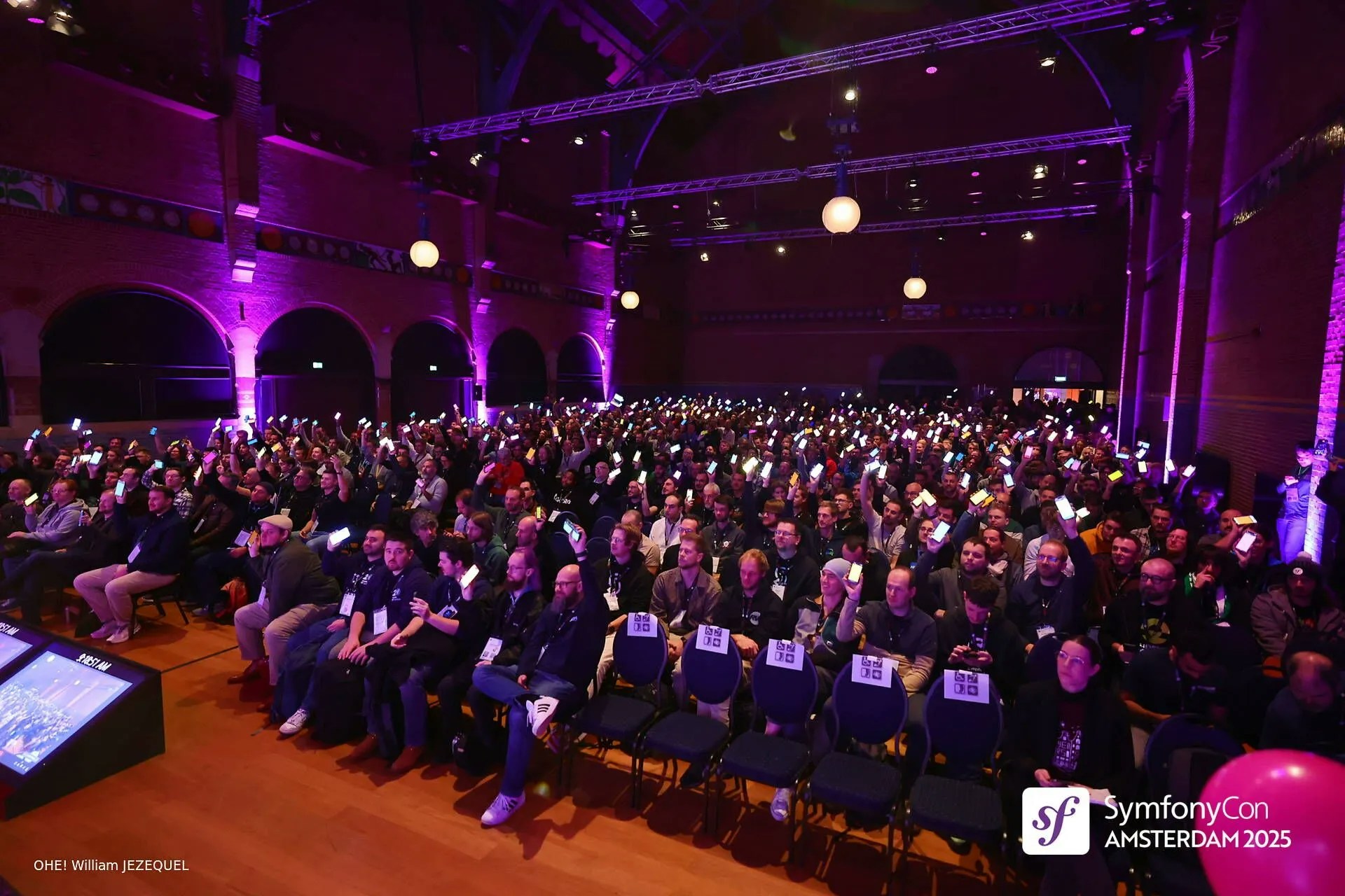 The SymfonyCon 2025 audience holding their phones up, showing lit screens in celebration